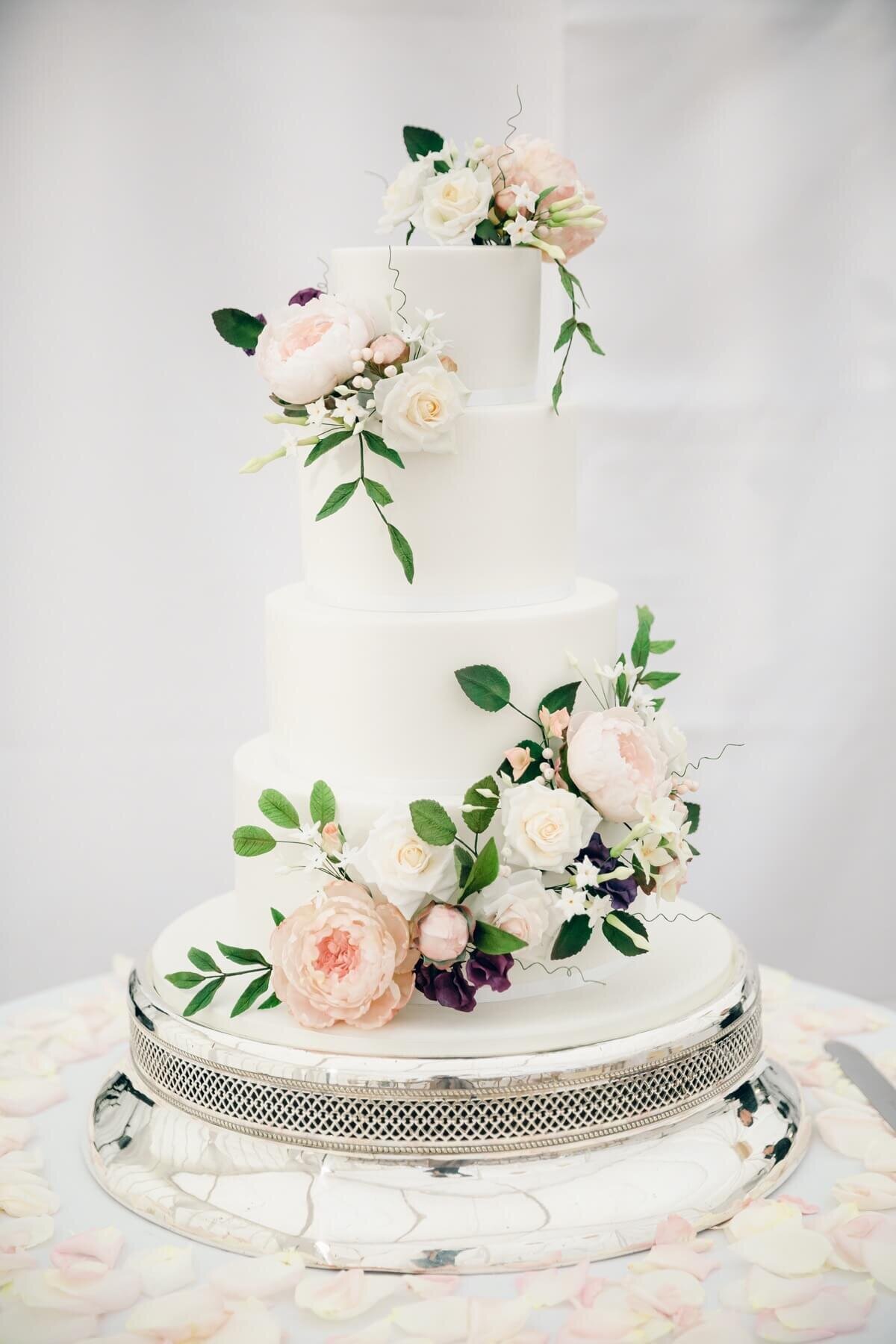 A white wedding cake with elengant flowers running diagonally down the cake