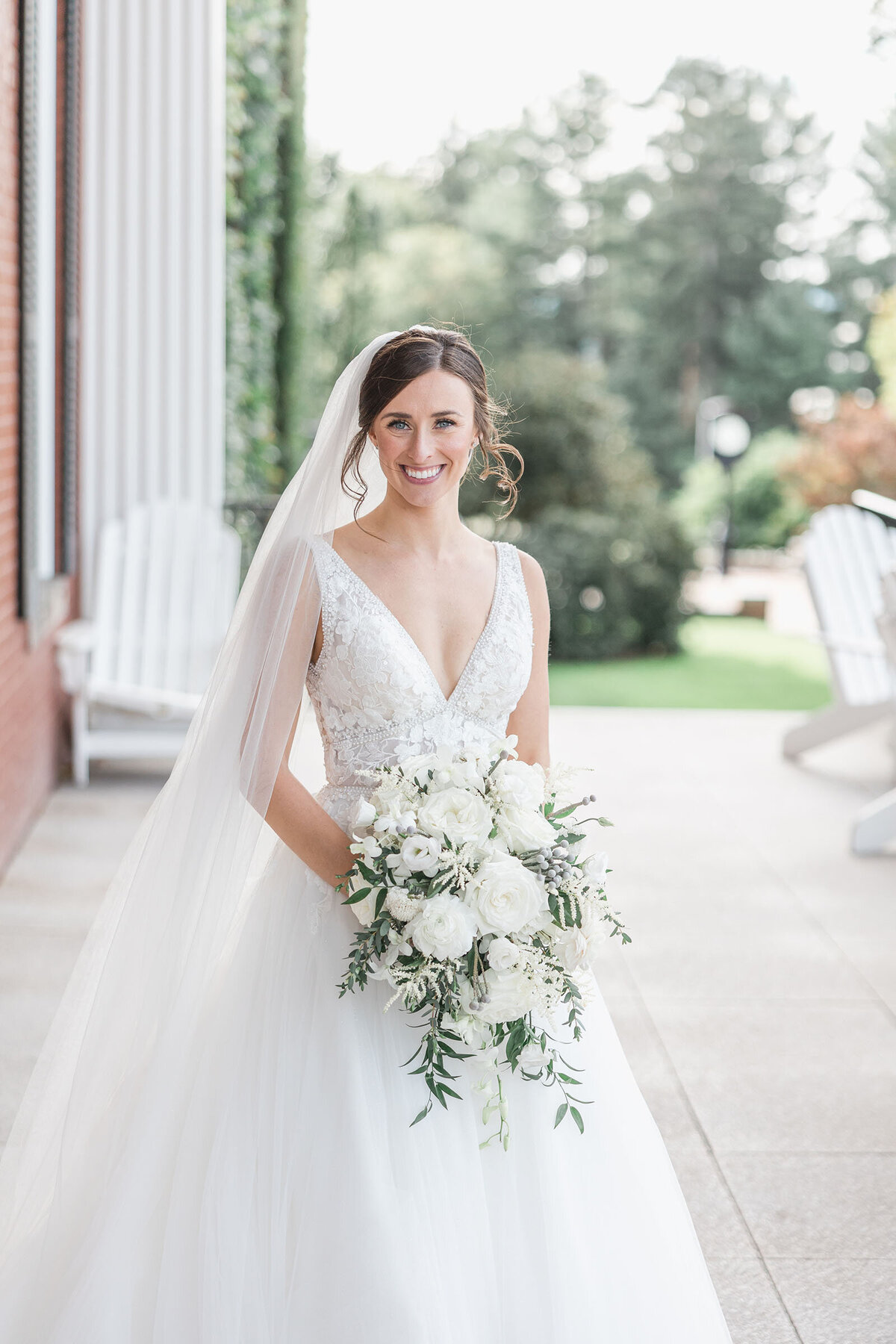 A portrait of a bride in her flowing A line gown holding her all white bridal bouquet