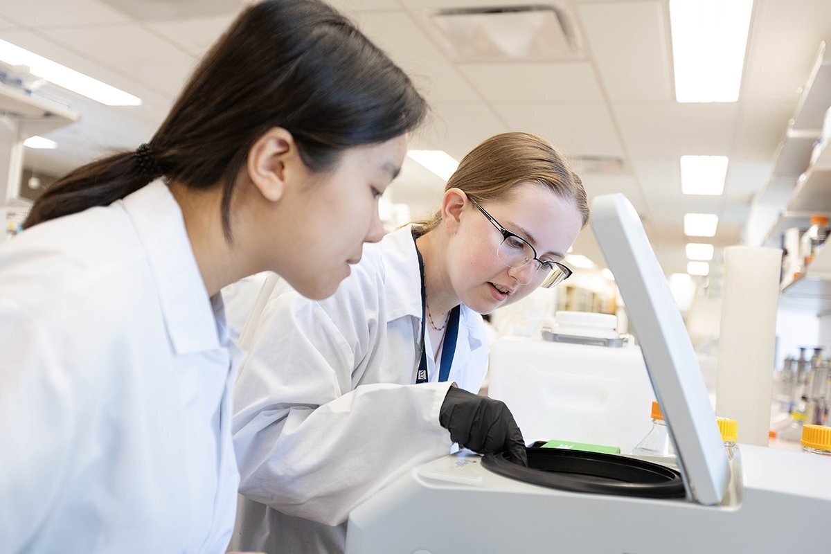 Female students looking into a centrifuge