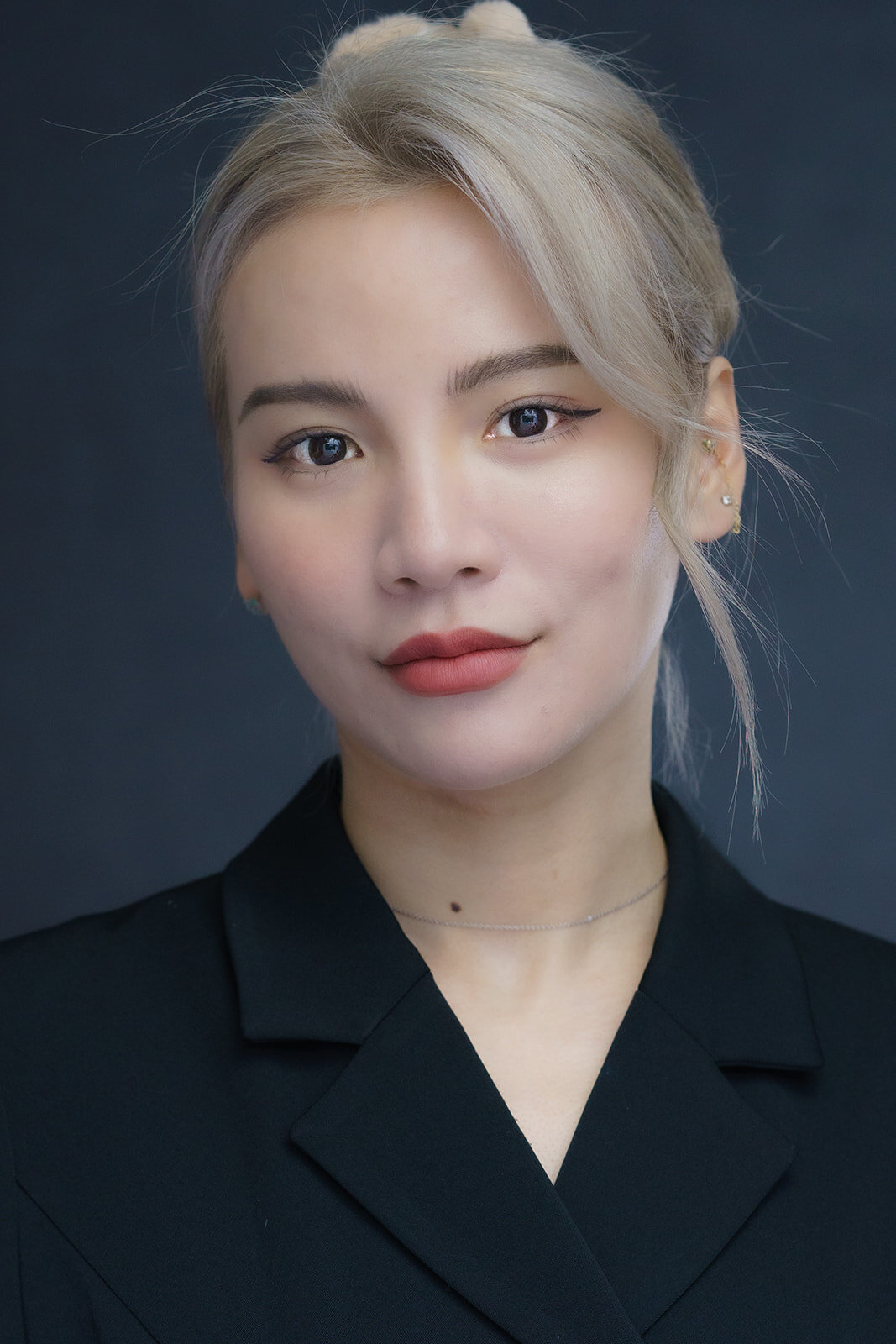 Close-up of an asian female executive in a dark suit with light colored hair