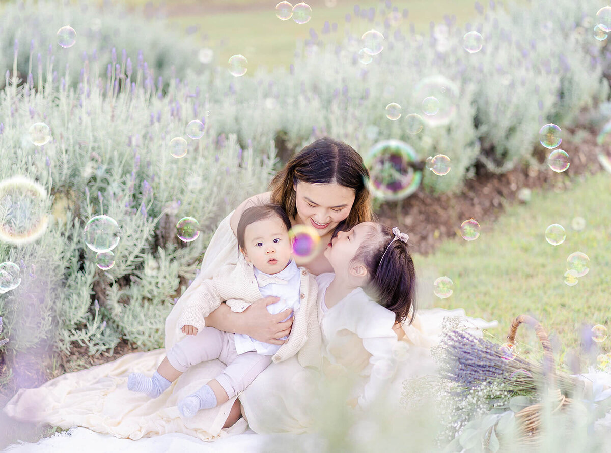A lifestyle intimate shot of mum cuddling her children lovingly in a flower field in Brisbane.