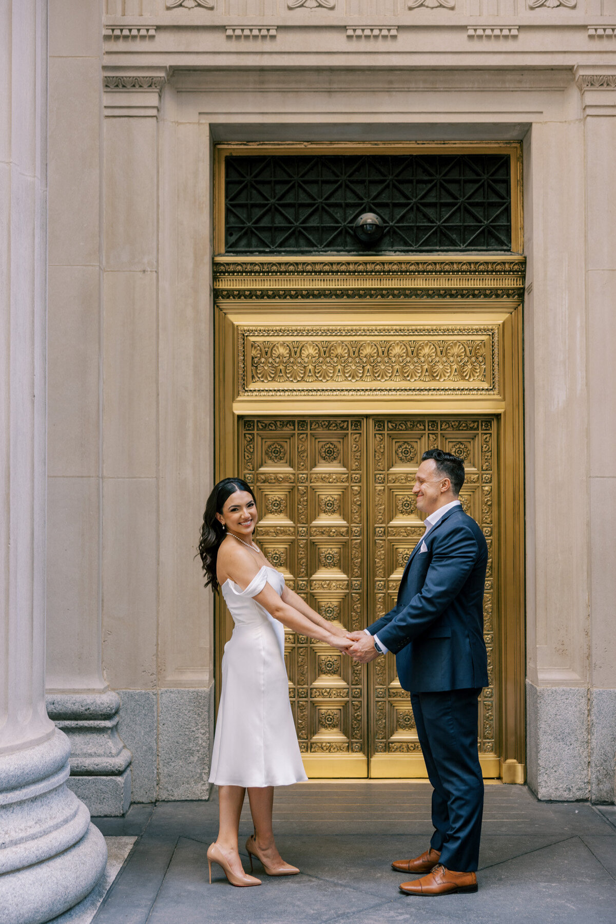 Couple pose in front of iconic gold doors in the heart of the city