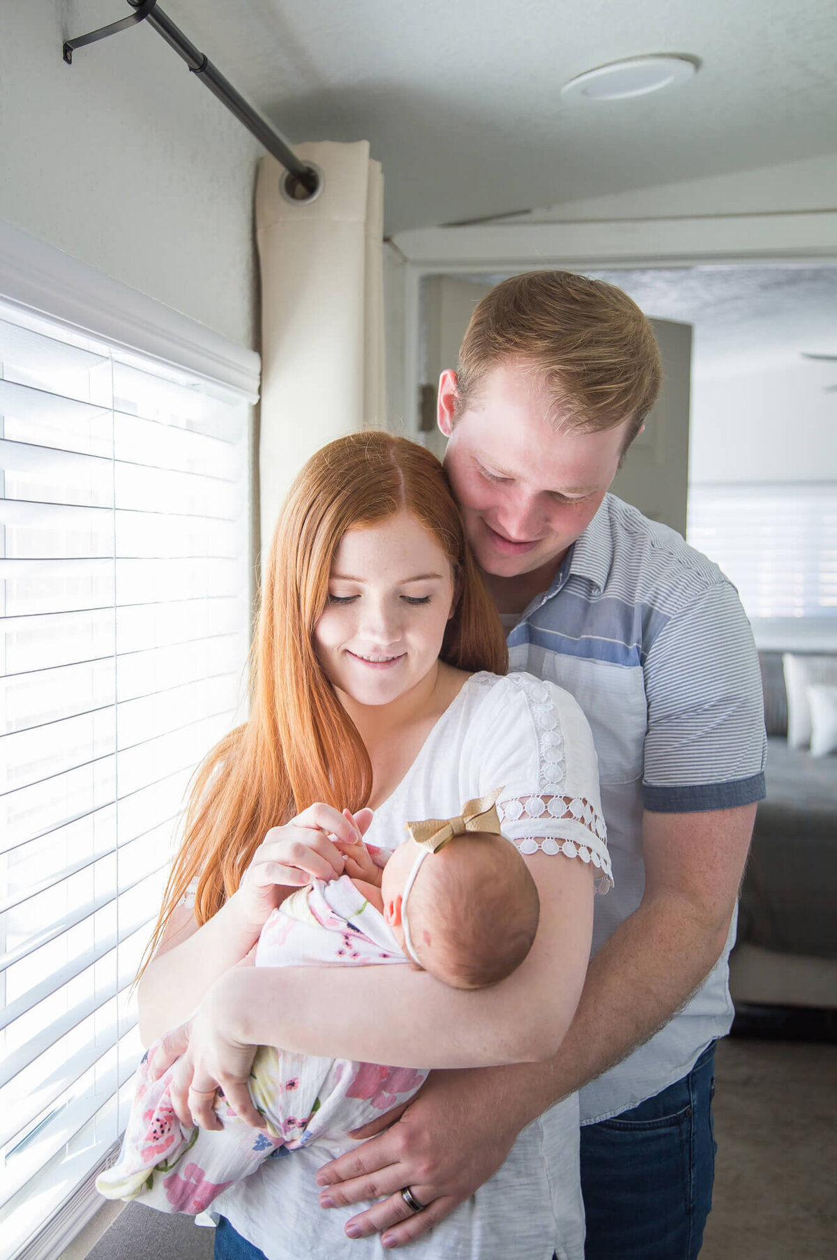 Couple holding newborn baby girl while thoughtfully looking down at her