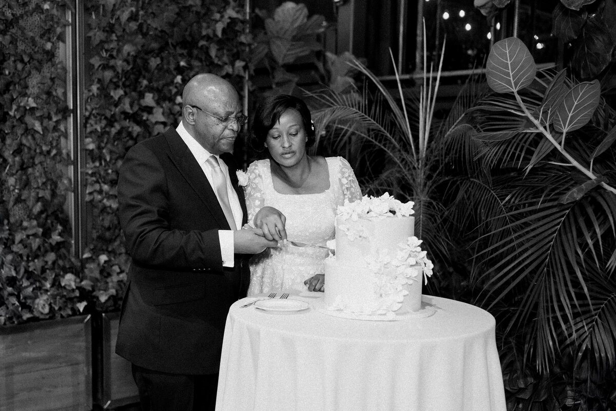 A newly wedded Black American couple cutting their wedding cake at the reception party