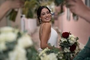 Smiling bride in white dress holding red and white bouquet during St Augustine wedding ceremony, captured by professional wedding photographer