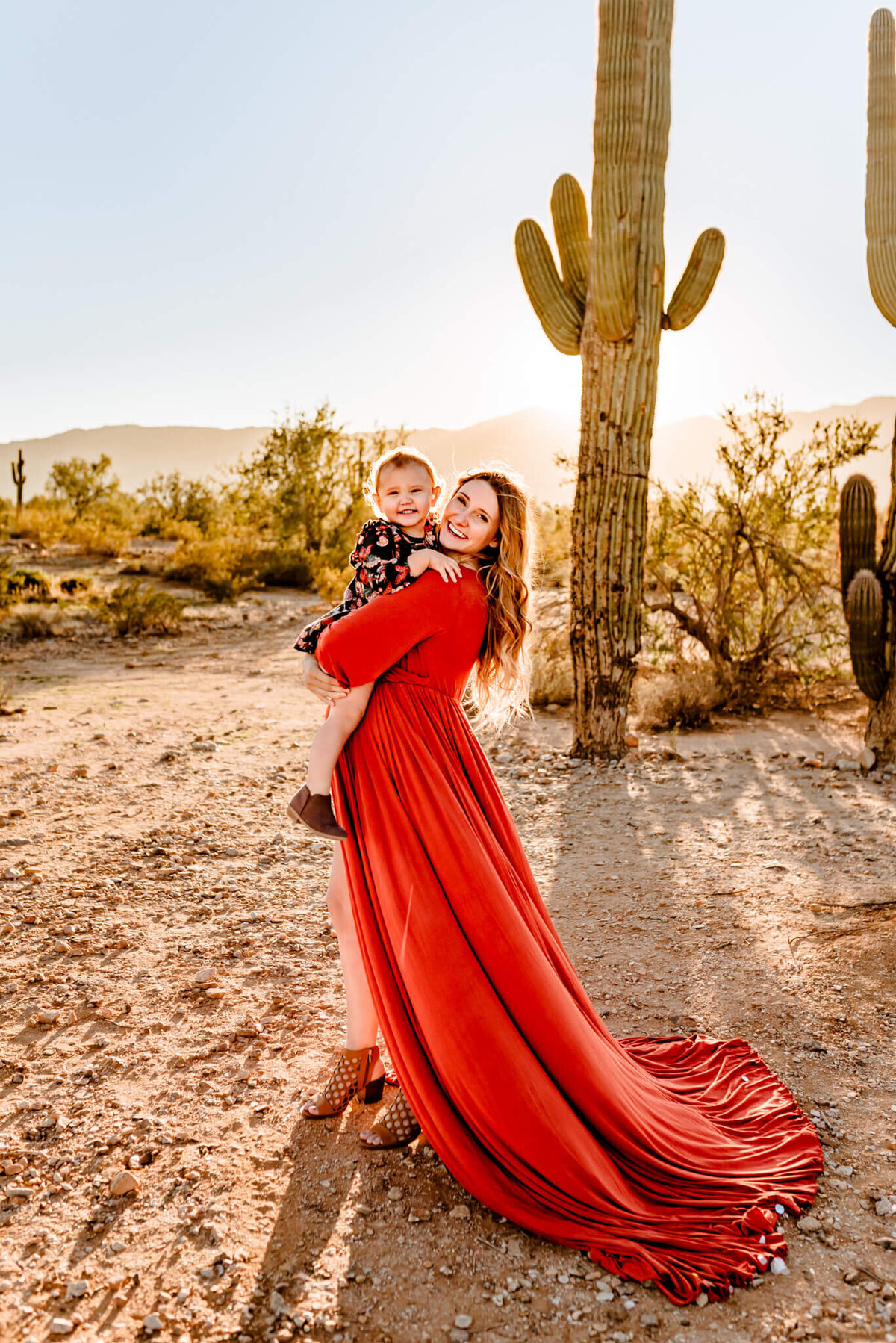 mom with rust maternity dress holding daughter for photograph in AZ