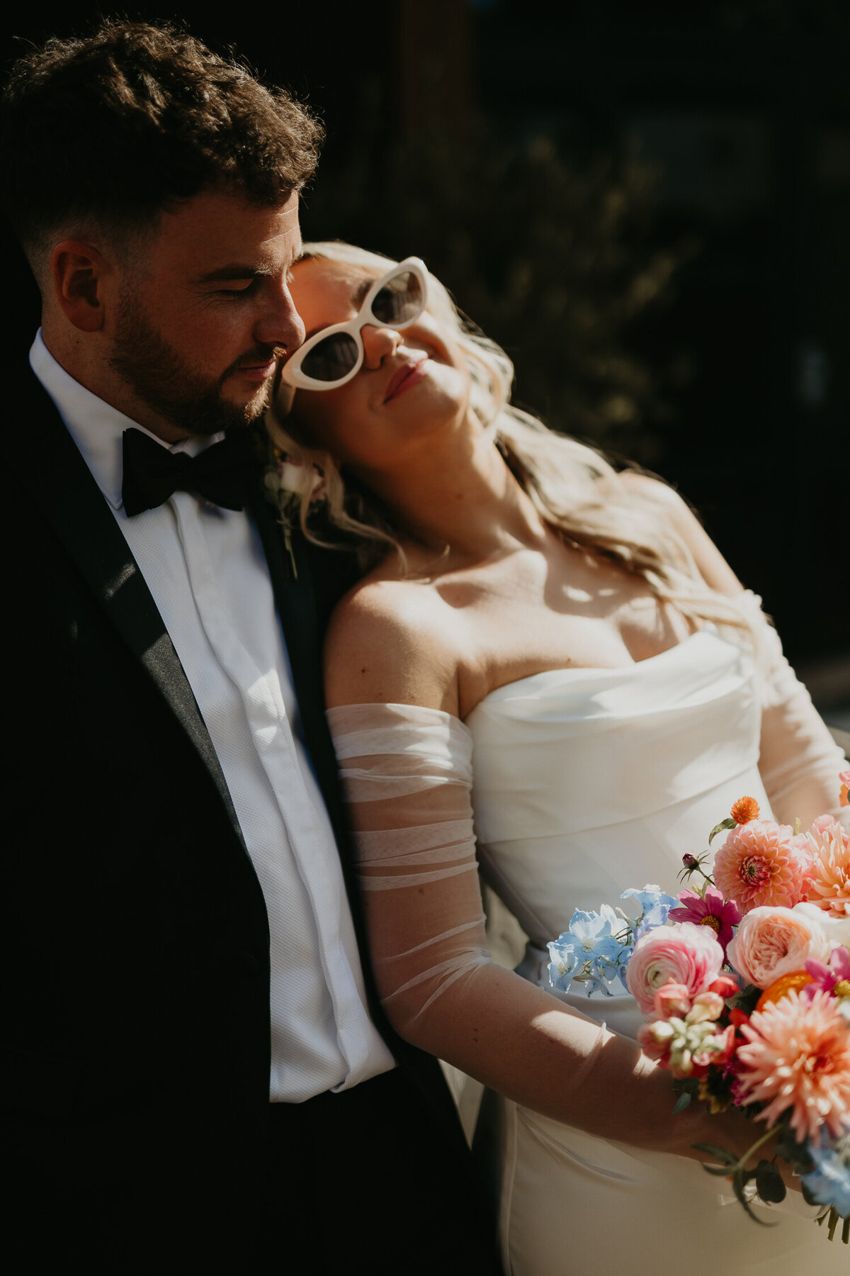Bride and groom sit on a vintage Triumph car at their wedding at The Shack Revolution. 