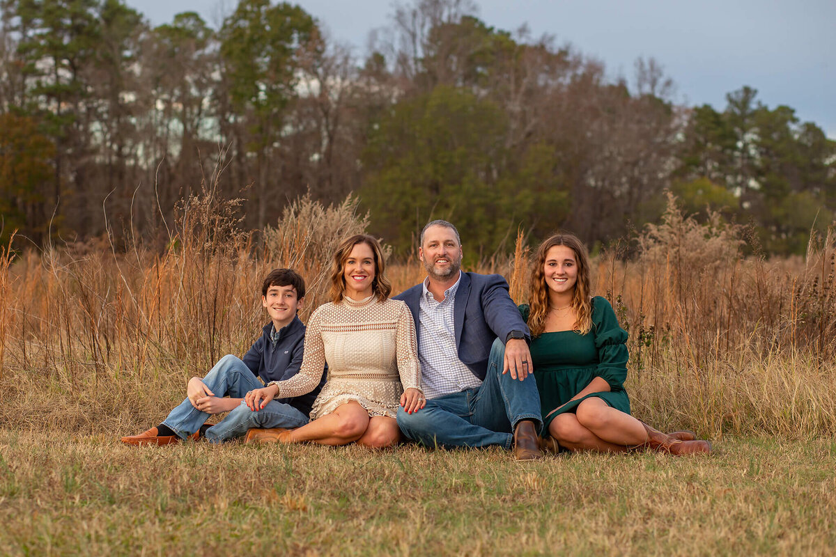 Beautiful family sitting in a fiend at sunset by Susan VanNess Photography, a Raleigh family photographer