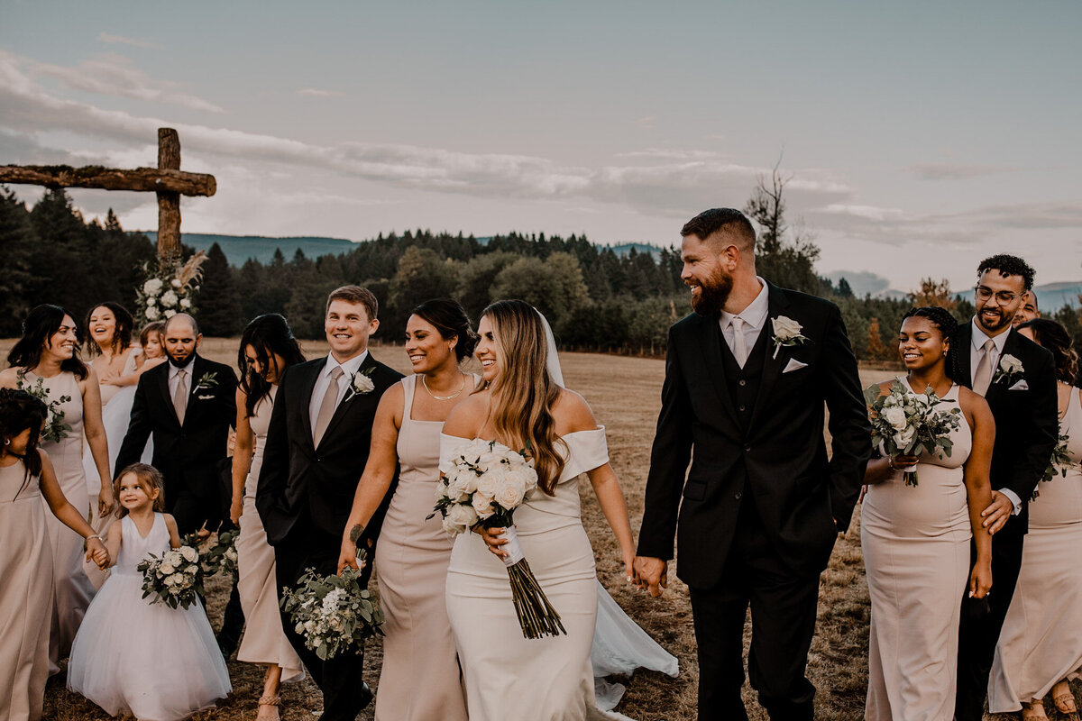 Bridal party walks with bride and groom in a large field