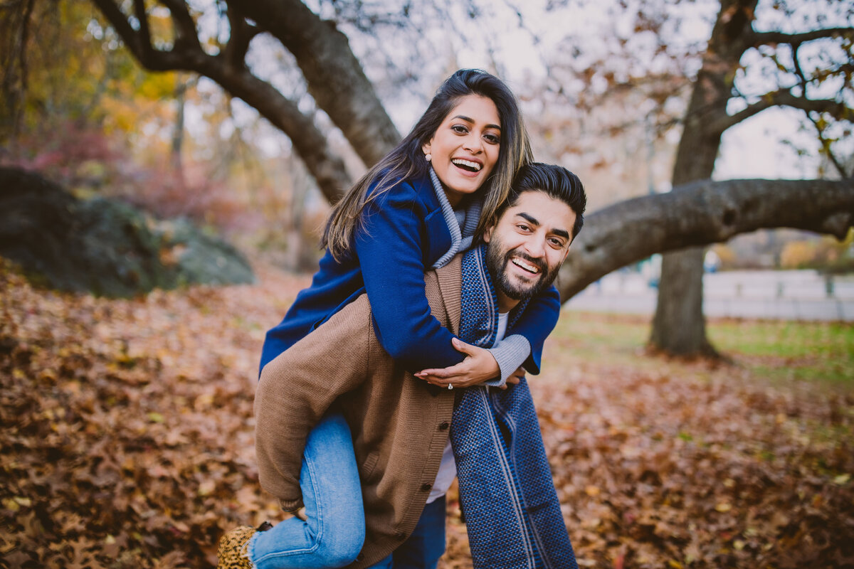 A couple doing a piggyback ride in the fall at central park nyc