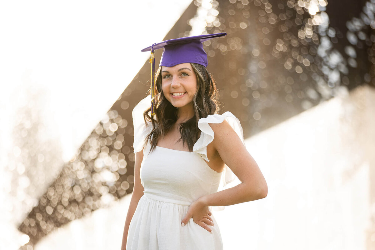 Senior college graduation photography session featuring a graduate wearing her graduation cap and a white dress.