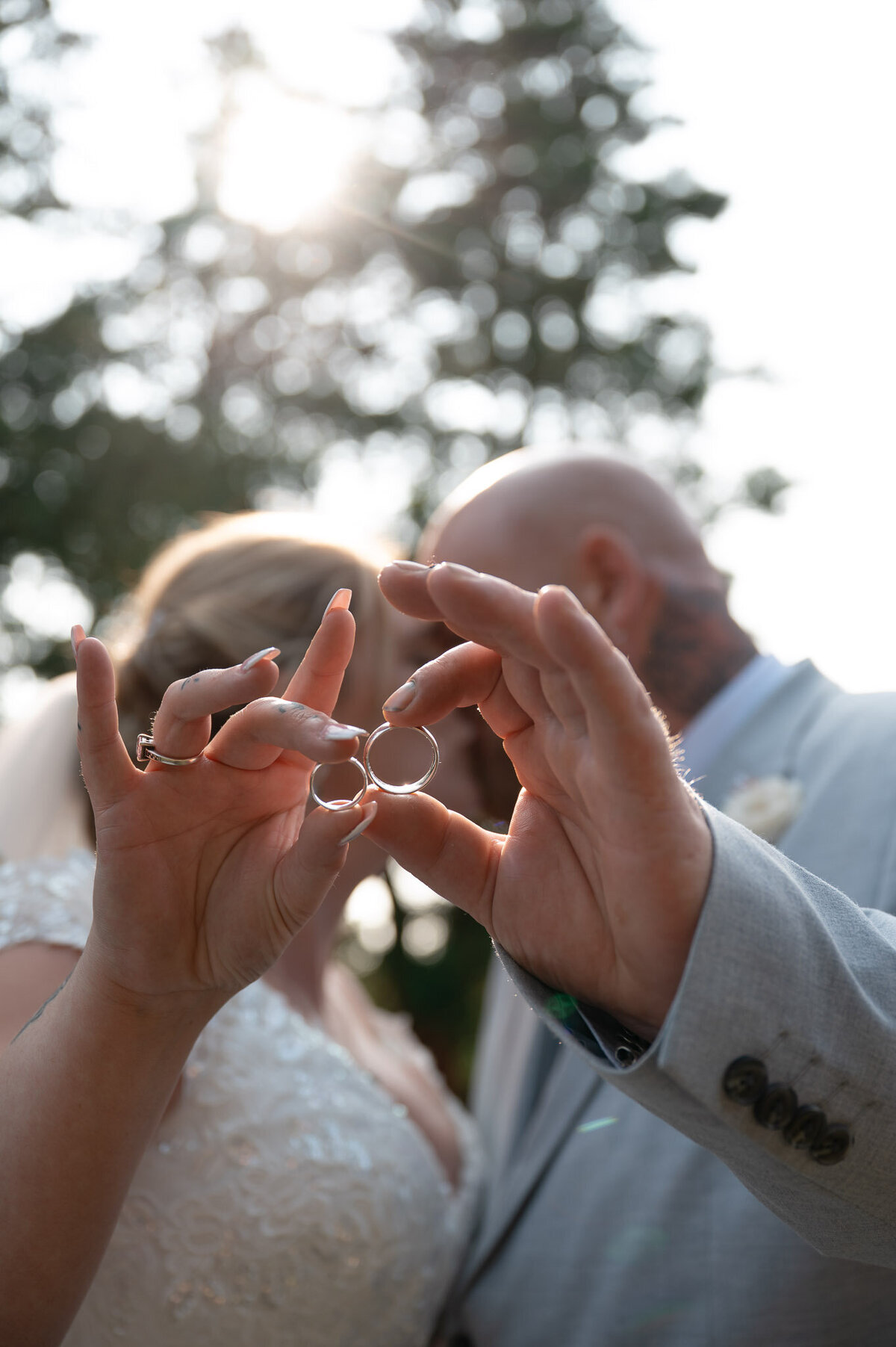 Bride and groom holding hands with wedding rings framed in sunlight – Manchester wedding detail.
