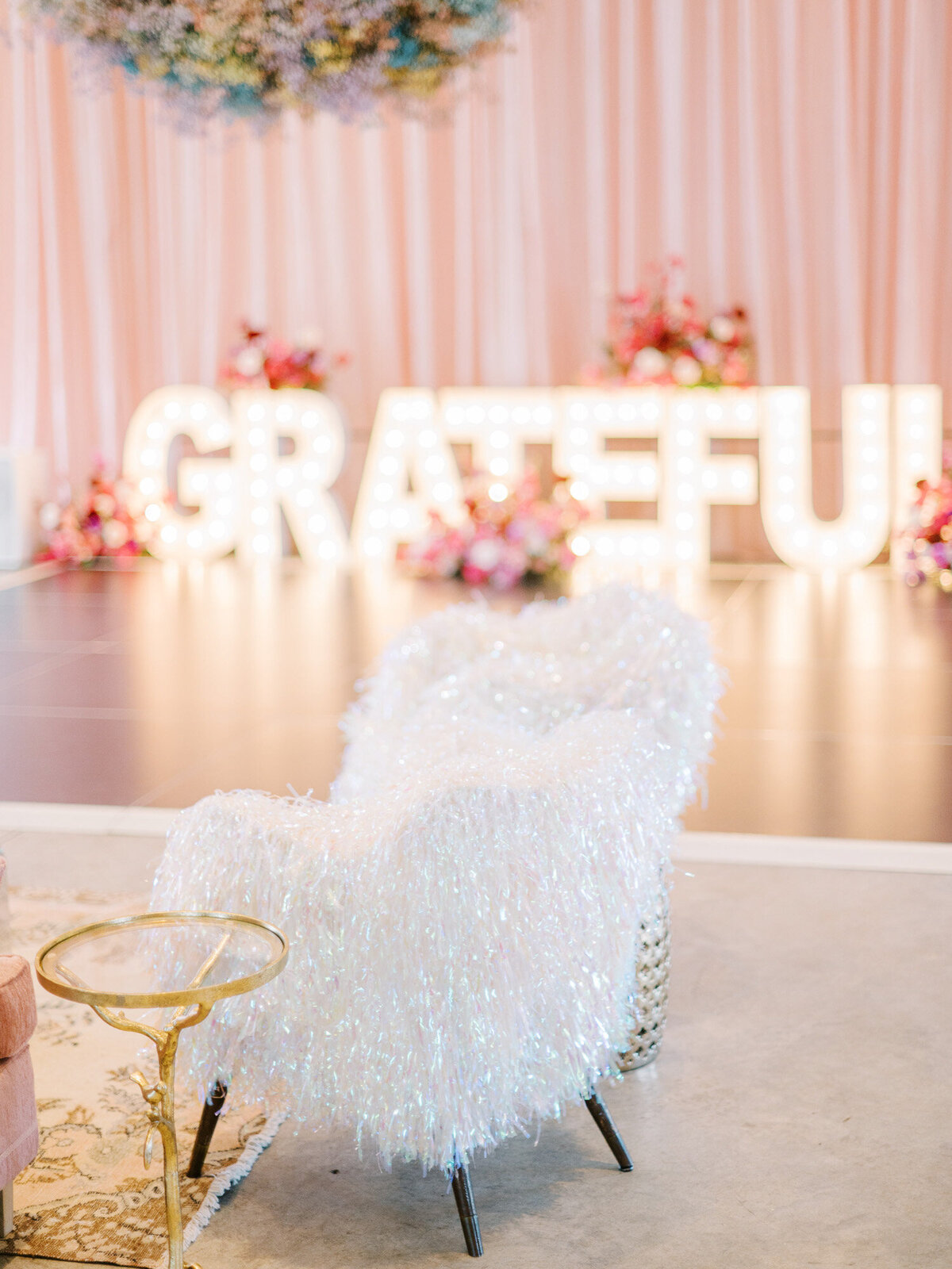 Grateful lit letters and an elegant white fur chair