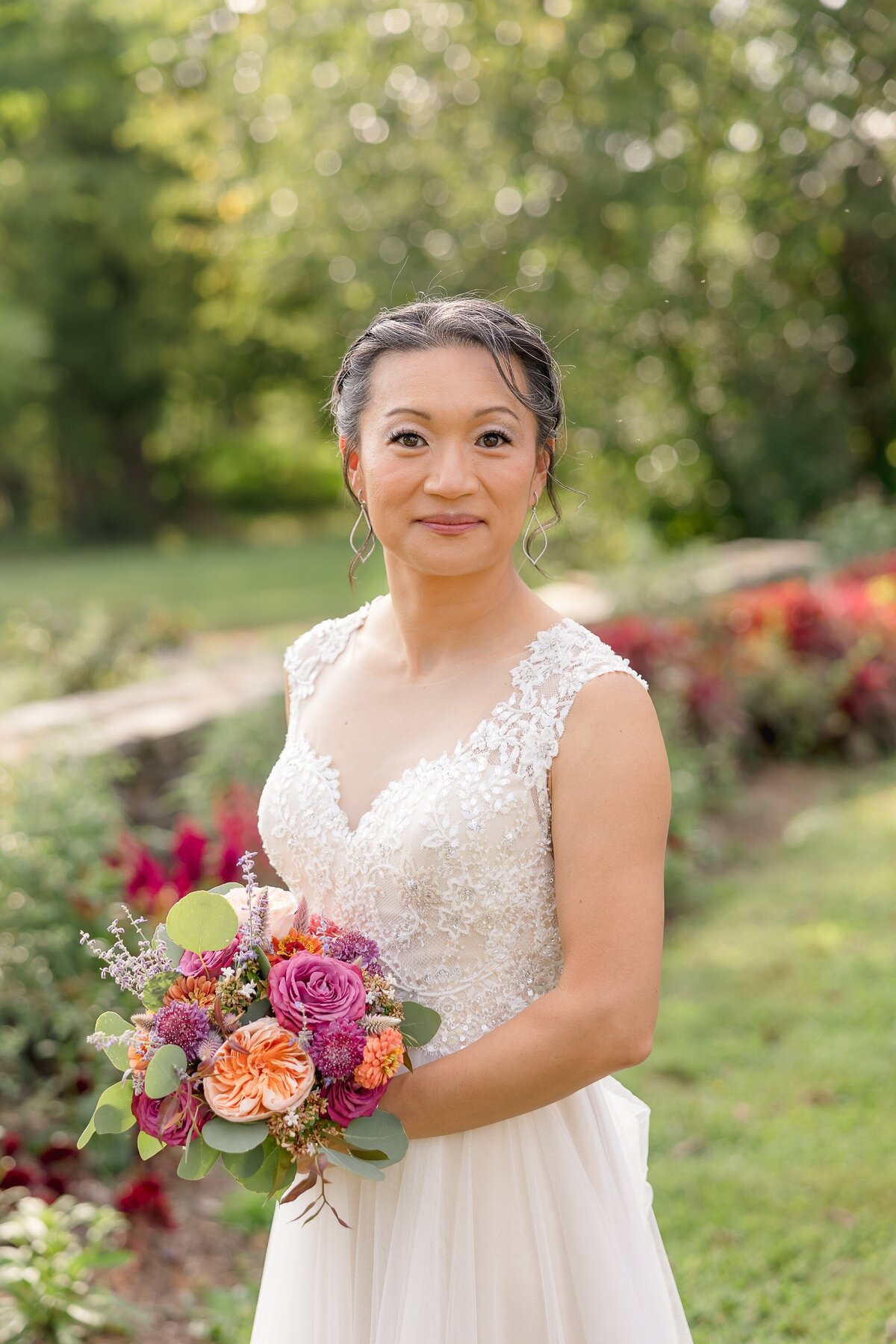 Bride holding a bouquet with different colored flowers stands outside during the springtime in the DMV
