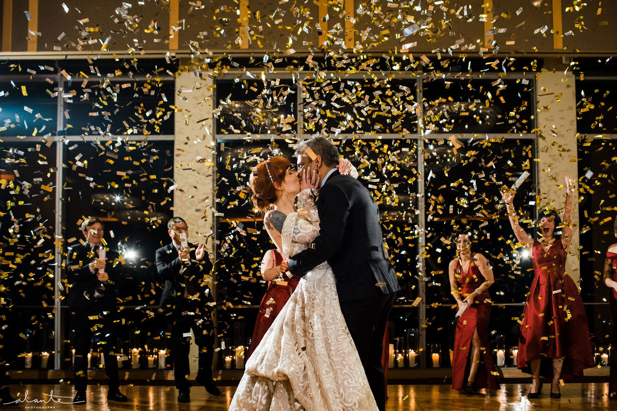 bride and groom dancing at their wedding with confetti falling from the ceiling
