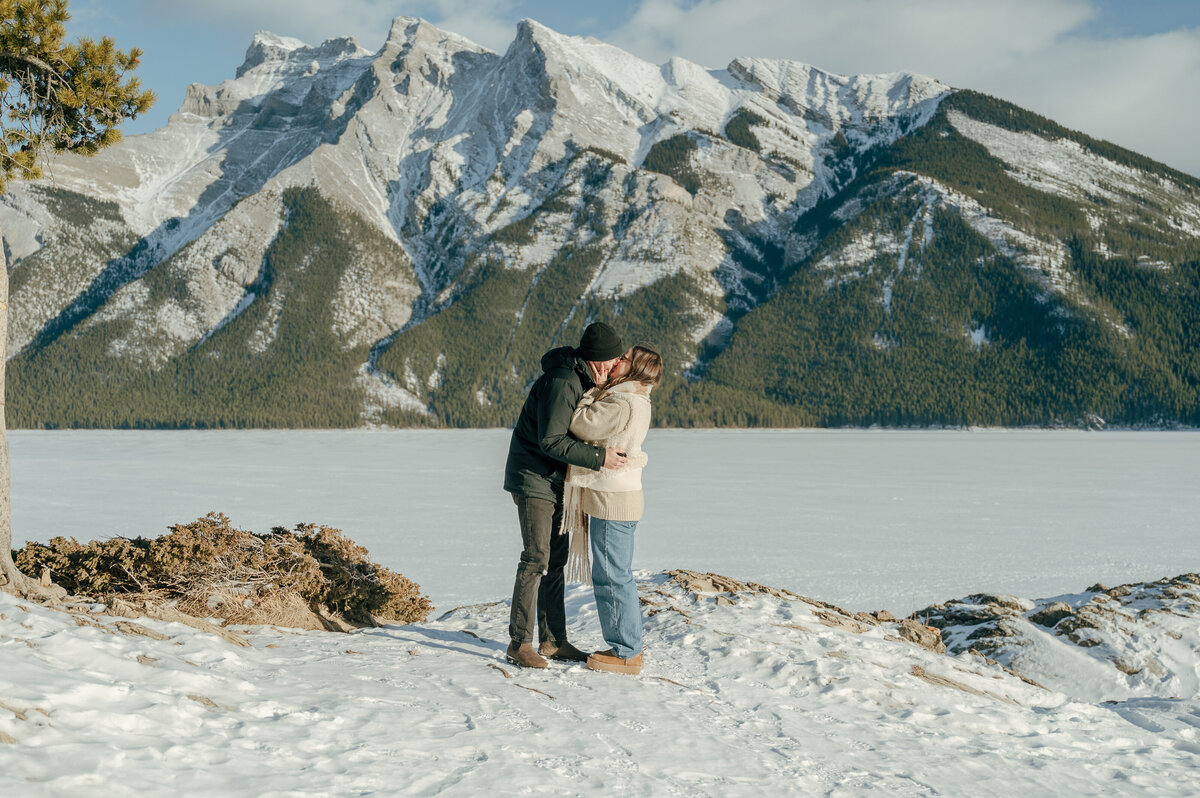 newly engaged couple embrace each other in Lake Minnewanka.