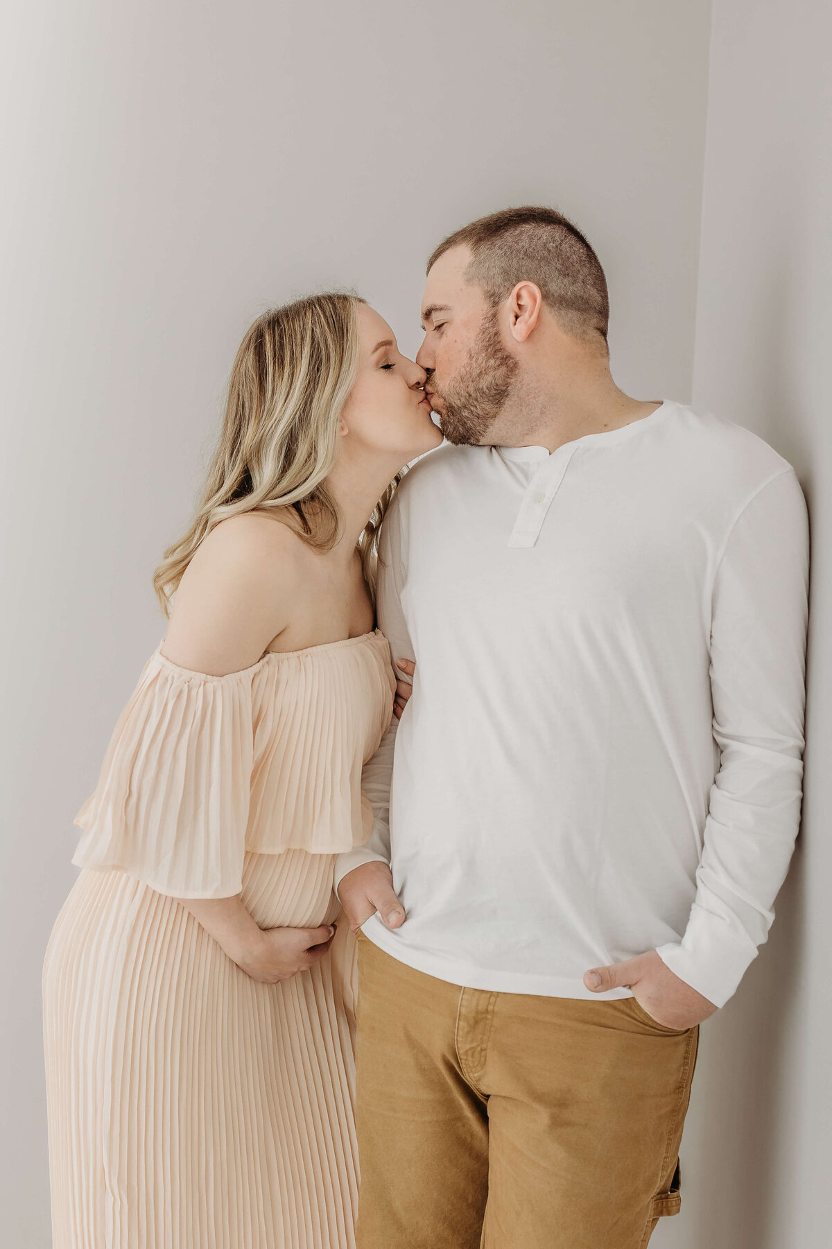 Husband and wife kissing expecting baby