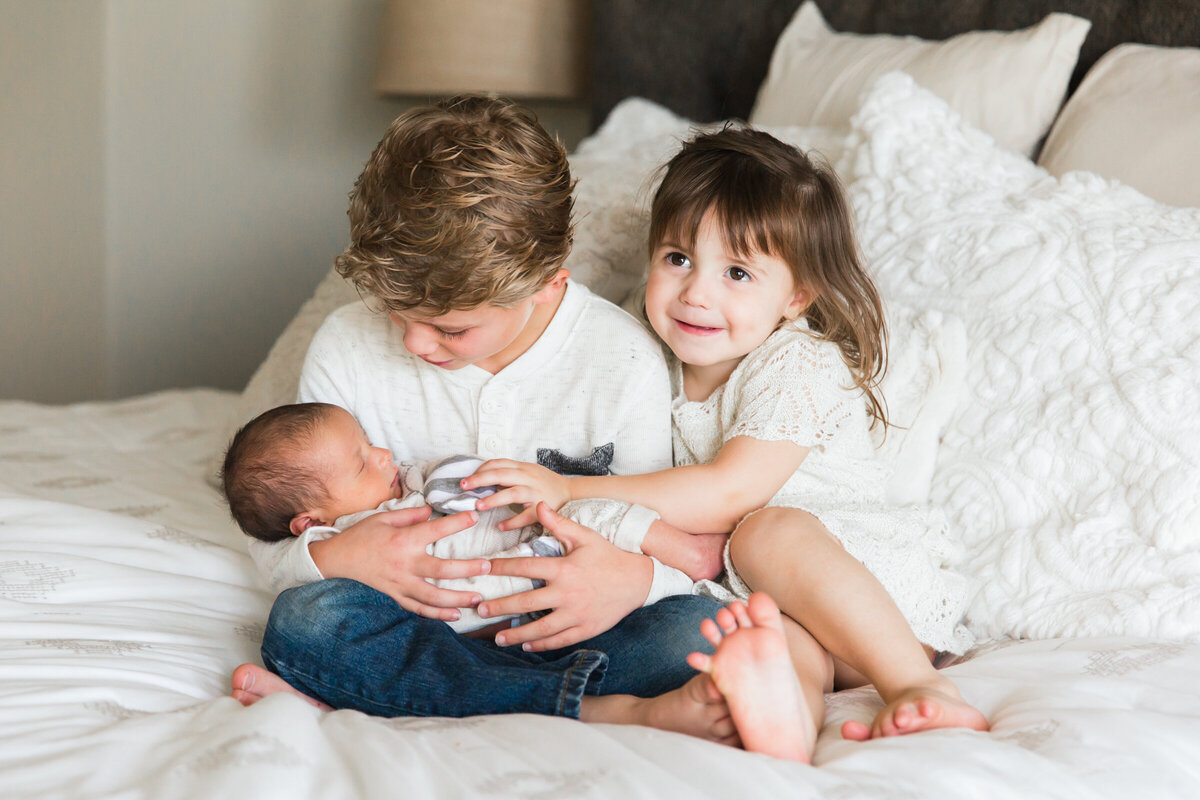 brother and sister holding newborn baby