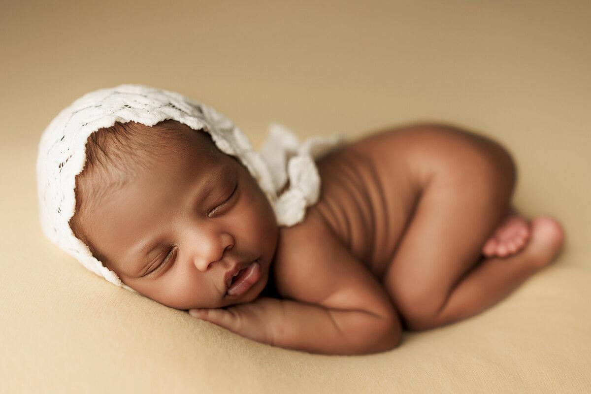 New baby girl laying on a yellow backdrop in a perfect pose