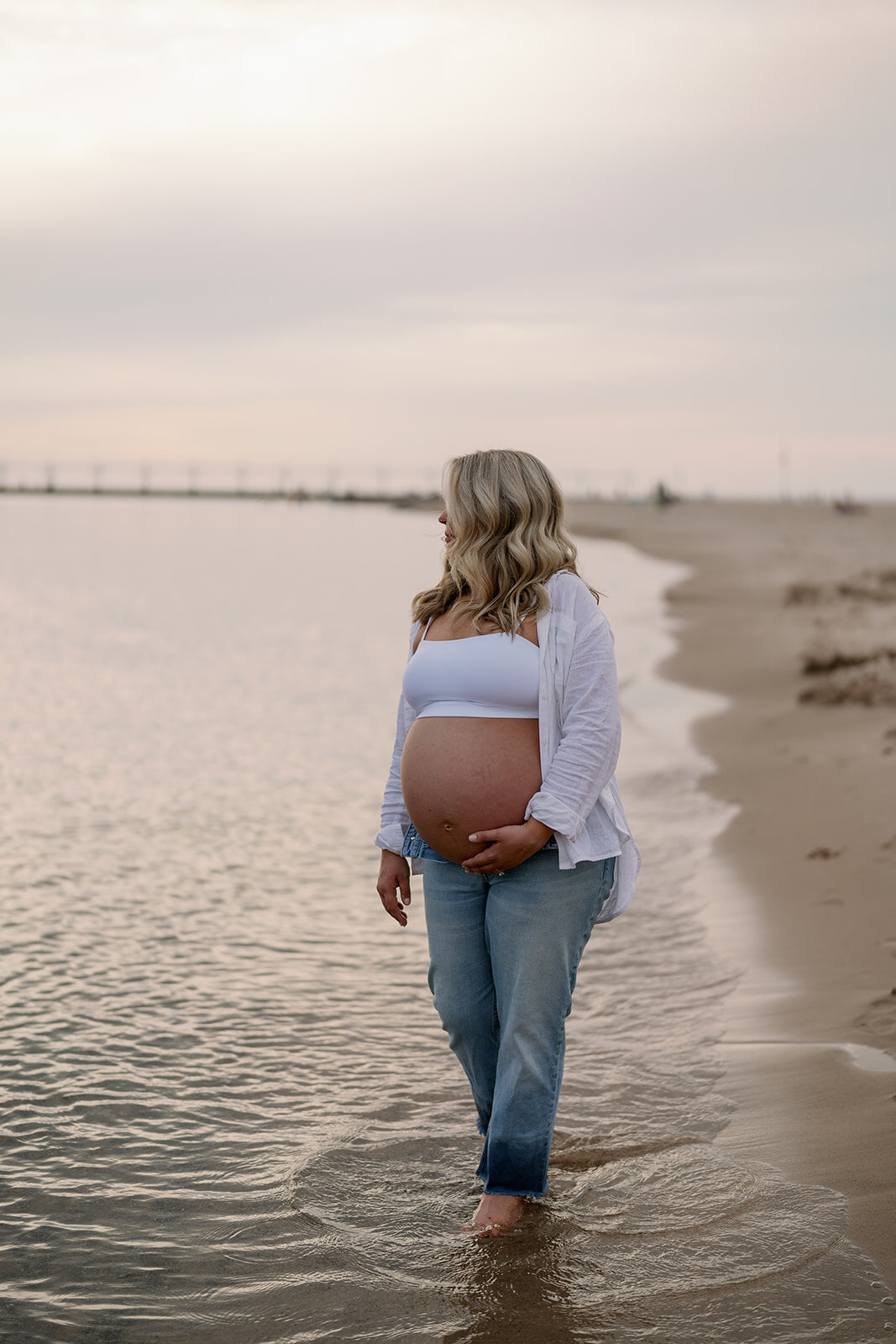Pregnant mother standing in Lake Michigan water during maternity photoshoot at South Haven North Beach.