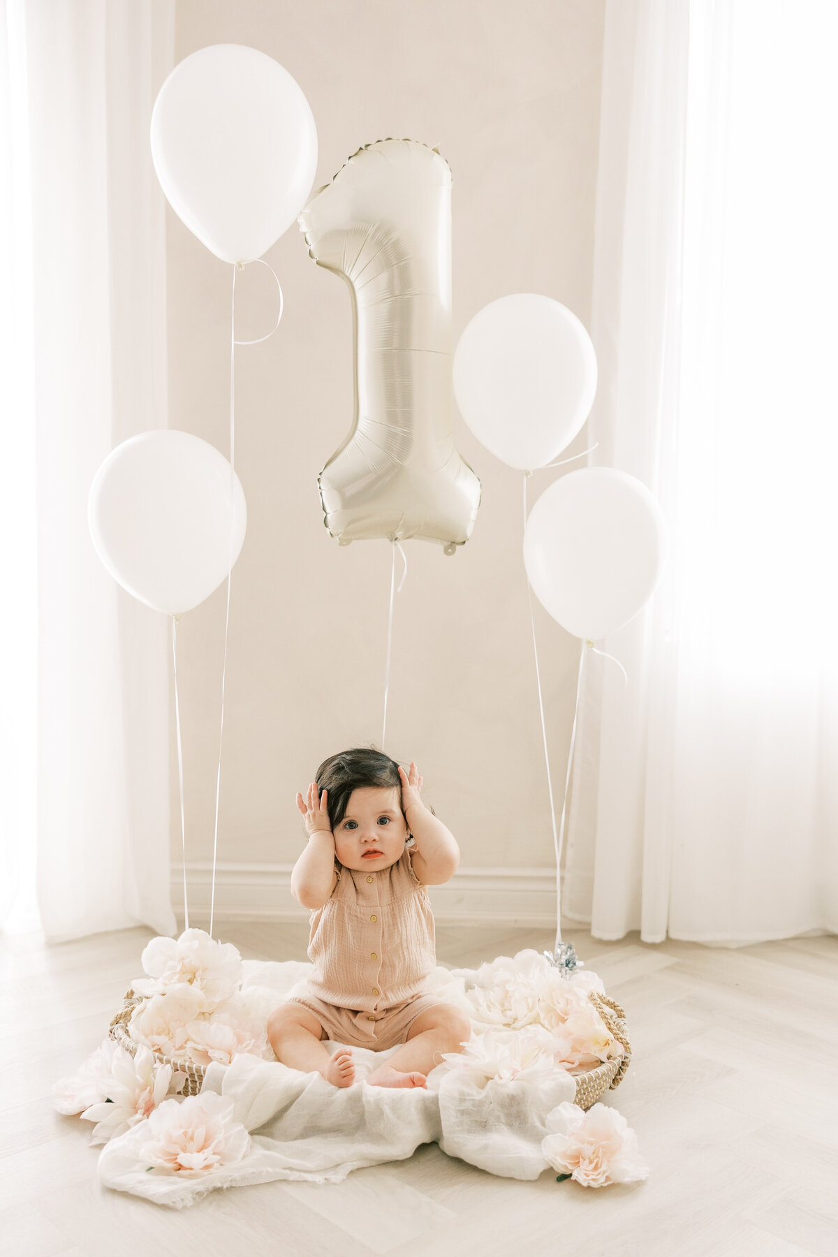 A 1 year old baby sitting in a basket with balloons in a Toronto Studio