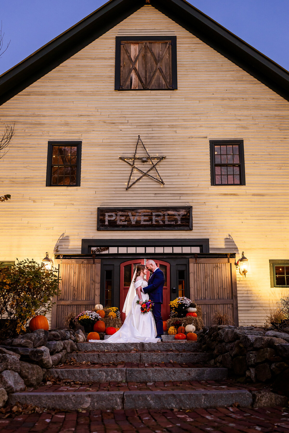 bride and groom looking into each others eyes in front of the iconic red doors at the Barn on the Pemi wedding venue in Plymouth NH