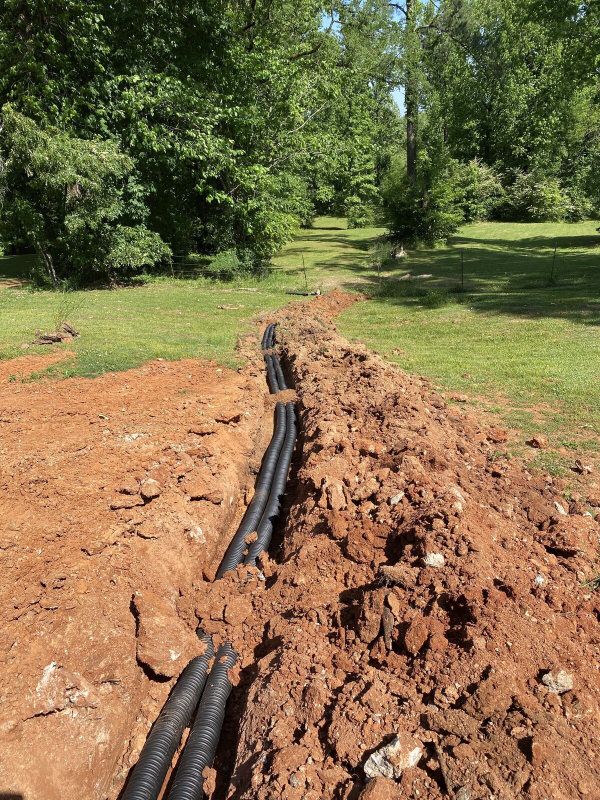 black-hoses-going-through-dirt-trench-in-backyard