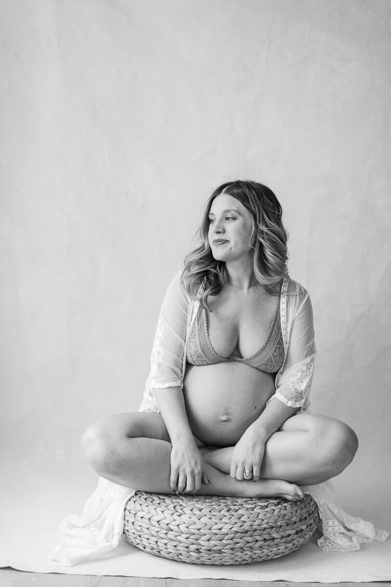 sitting with cross legs pregnant mom looks out studio window