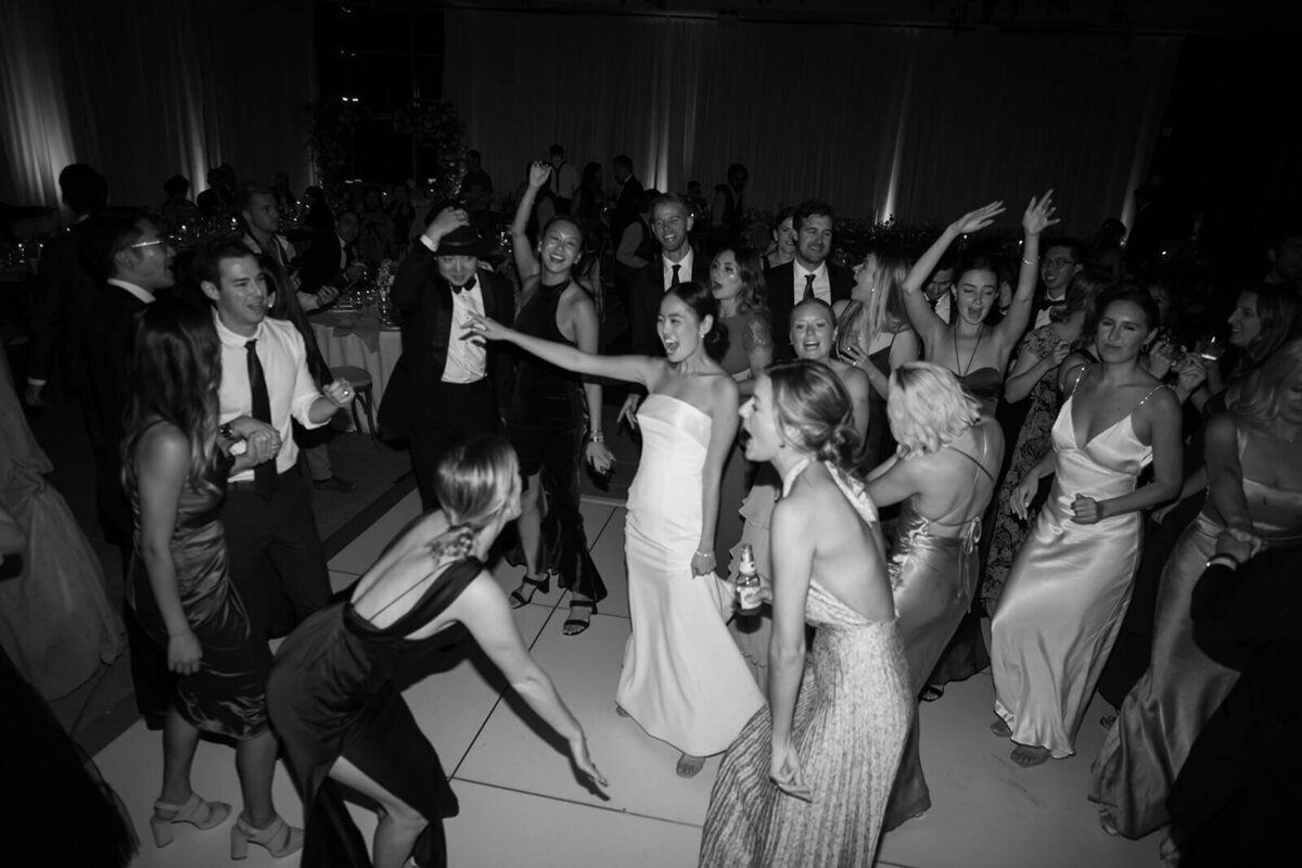 A black and white image of the newlywed couple dancing among all of their guests on the dancefloor of their Aspen Meadows Resort wedding reception.