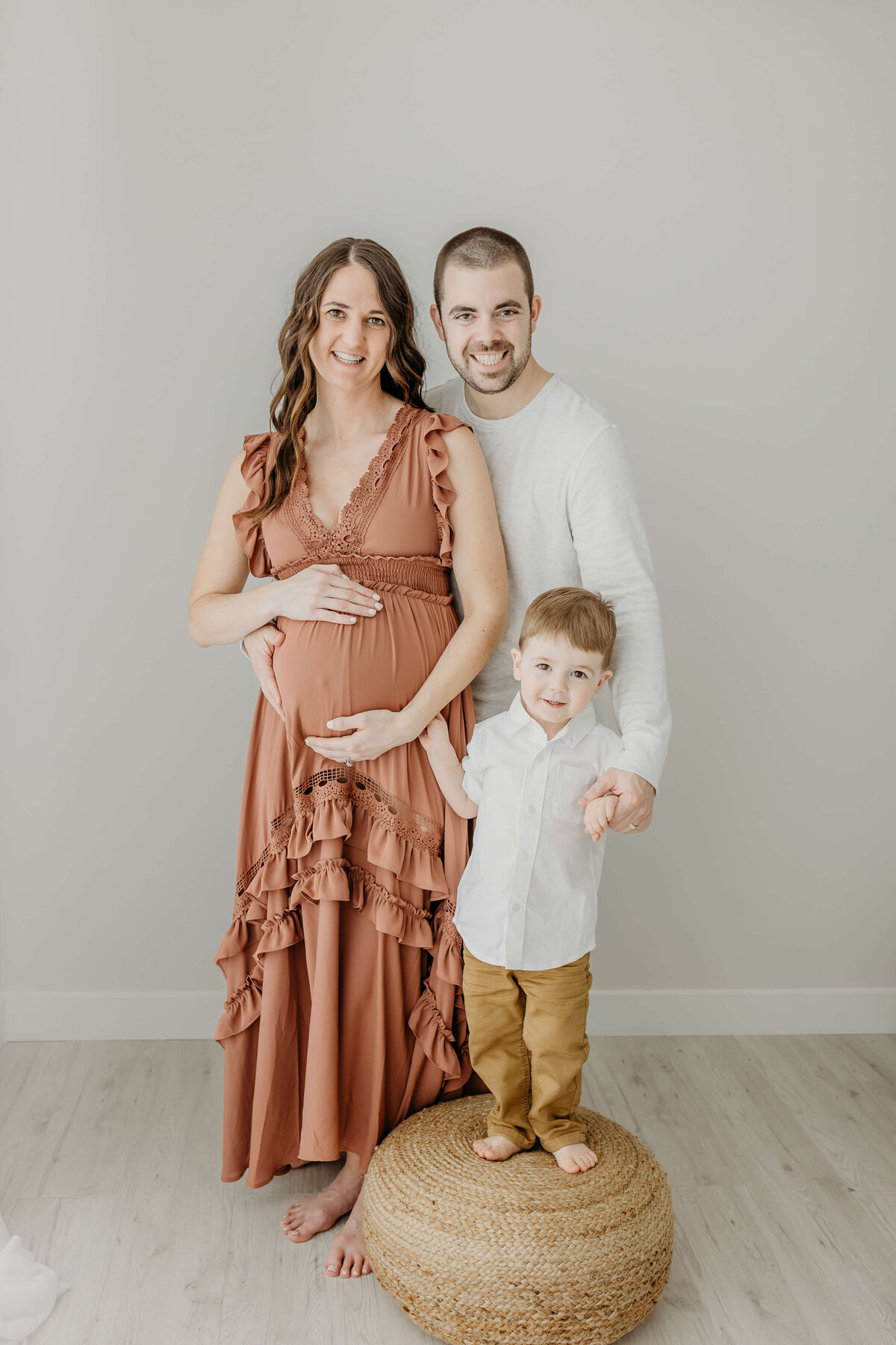 Young family smiling for maternity portraits in studio near Eau Claire WI