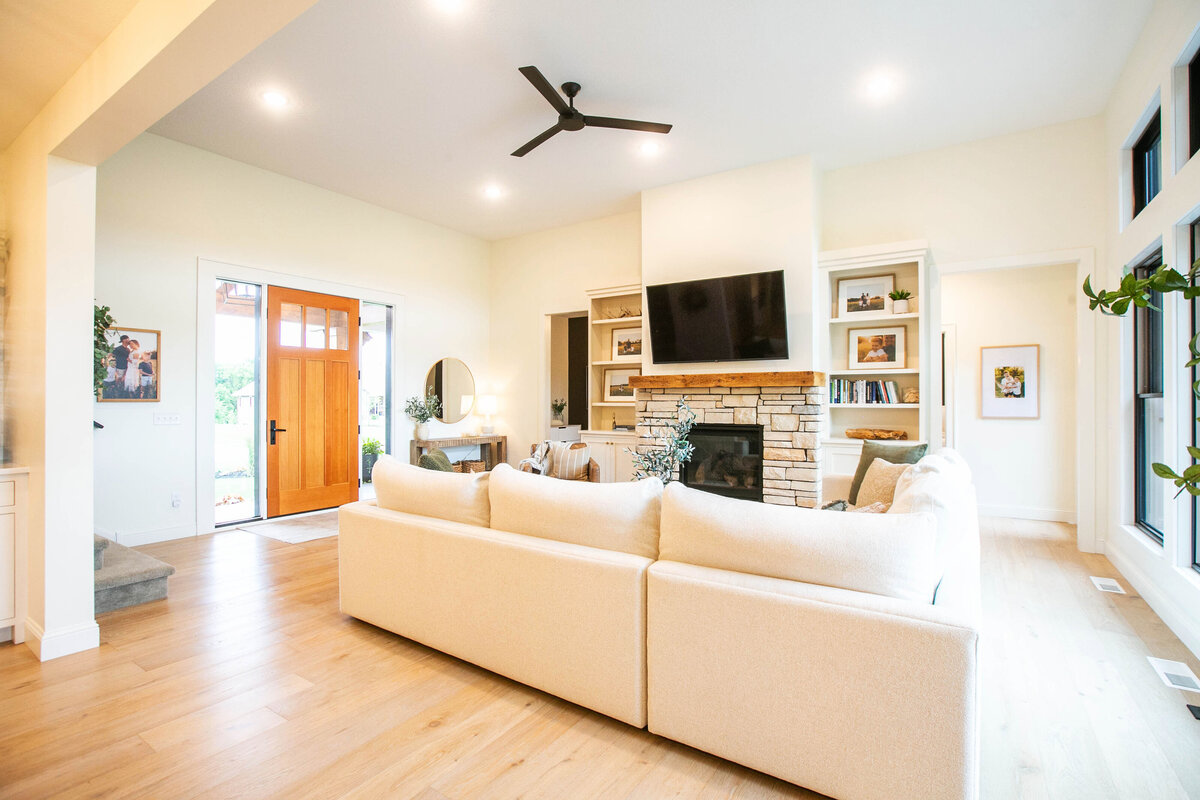 Cozy living room in Otsego custom home with fireplace, built-ins, and large windows