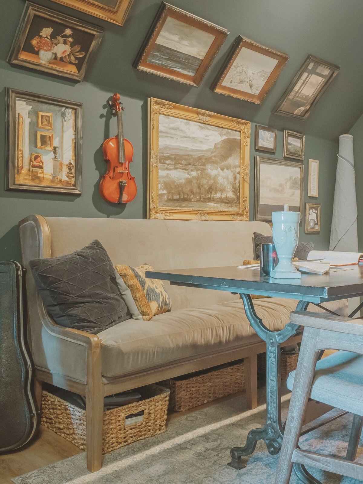 Sofa bench and gallery wall with wrought iron table and wooden padded chairs