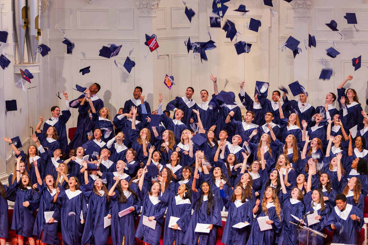 High school seniors in cap and gown throwing their gown in the air during the graduation ceremony in Atlanta by Laure Photography