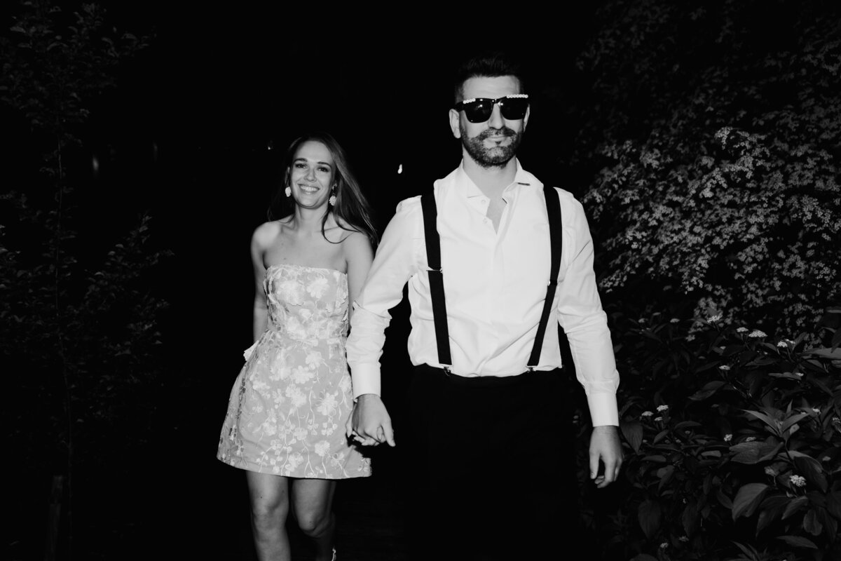 Bride and groom walking hand in hand at night during a fun wedding at Royle Forest Weddings in Derby, wearing stylish modern outfits with joyful expressions.