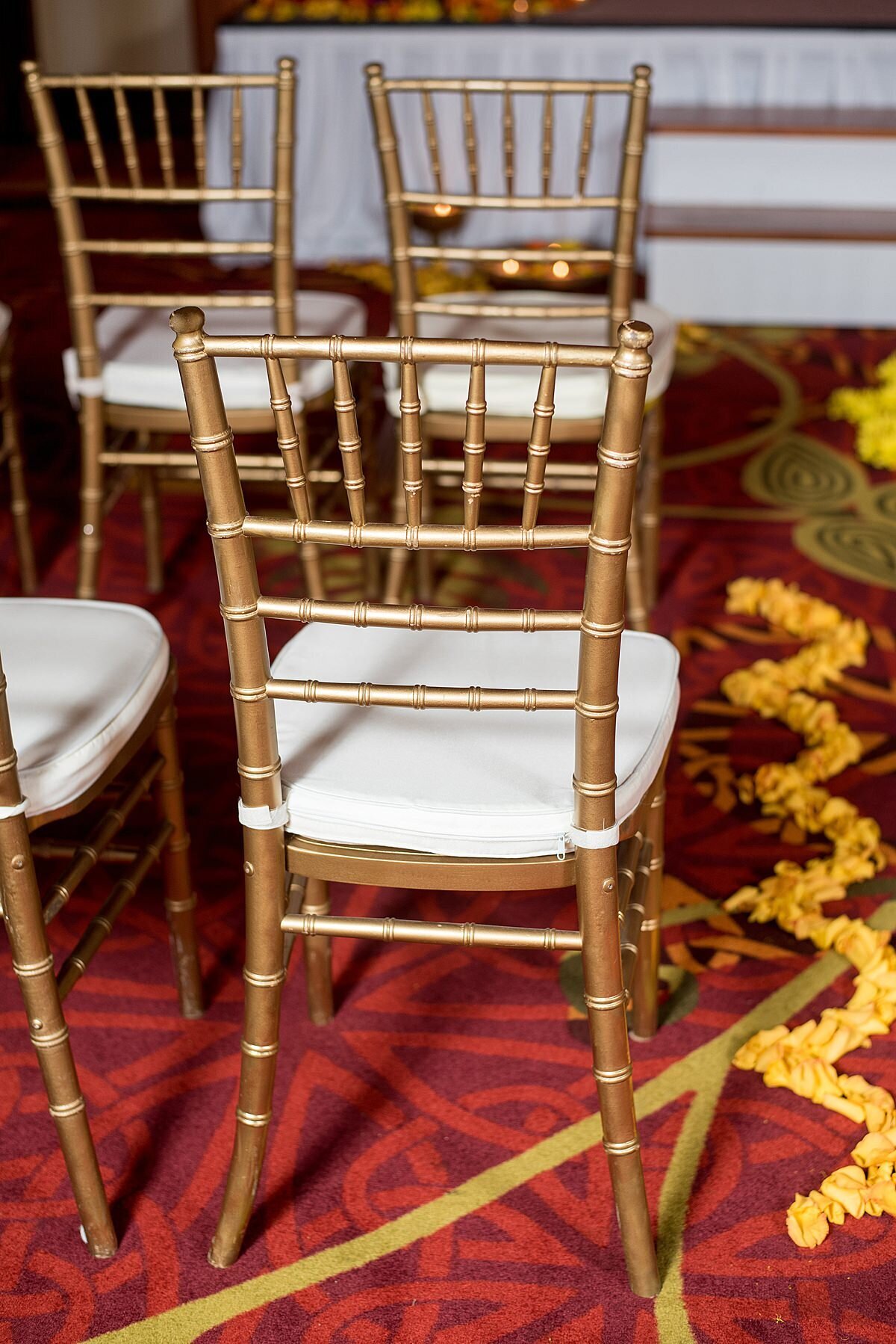 gold chivari chairs with white cushions on a red carpet with yellow flower petals lining the aisle at an Indian wedding in Nashville, TN