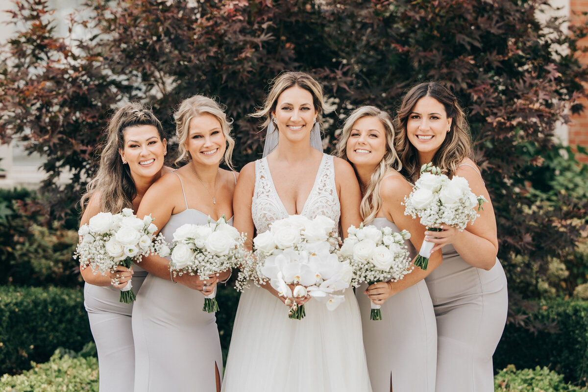 Bridesmaids holding white bouquets posing for fun photos
