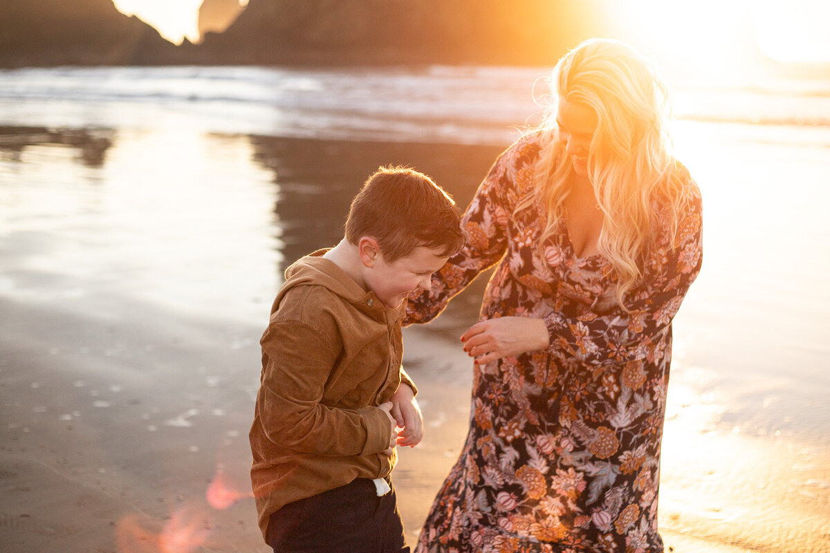 Mother and son laughing on the Oregon Coast at sunset.