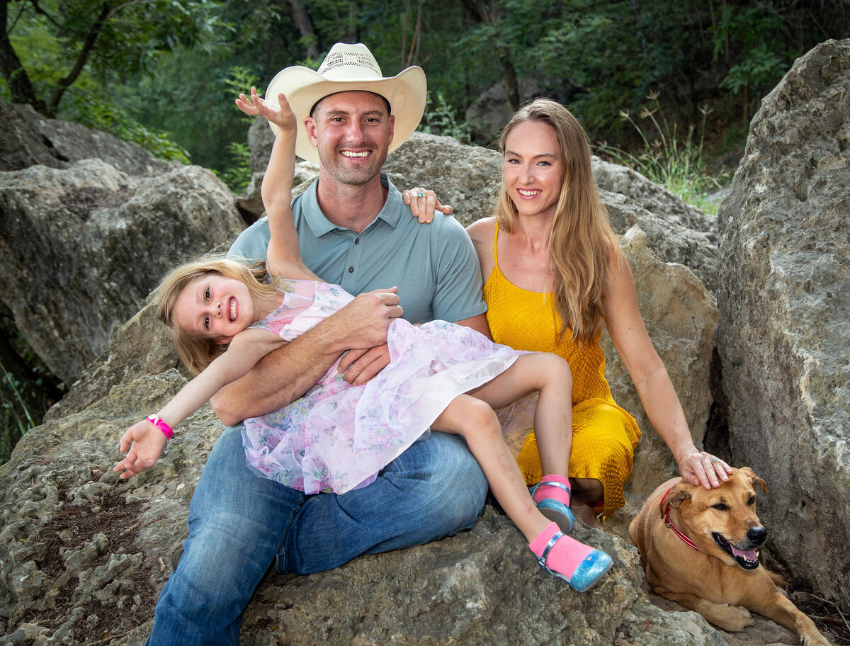 family of three with girl being excited and dog laying next to them