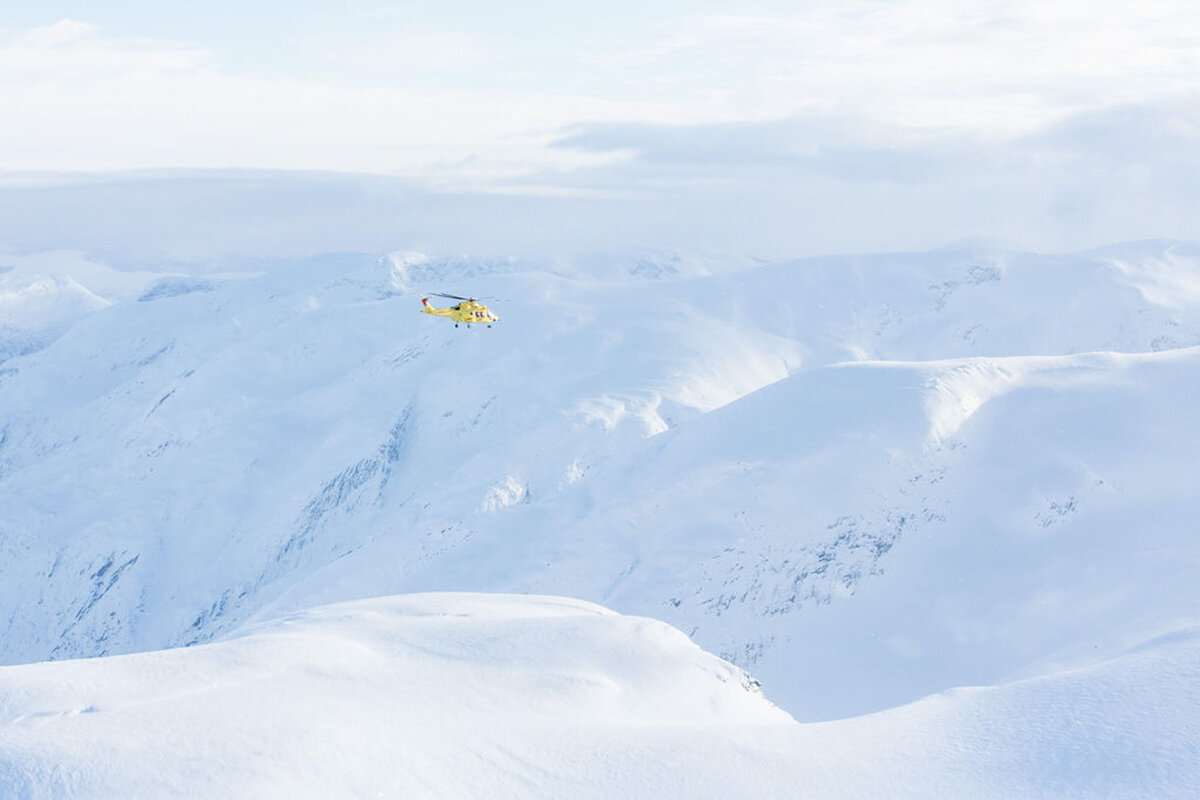 A private helicopter flying over snow-covered mountain peaks on a bespoke House of Imara journey.