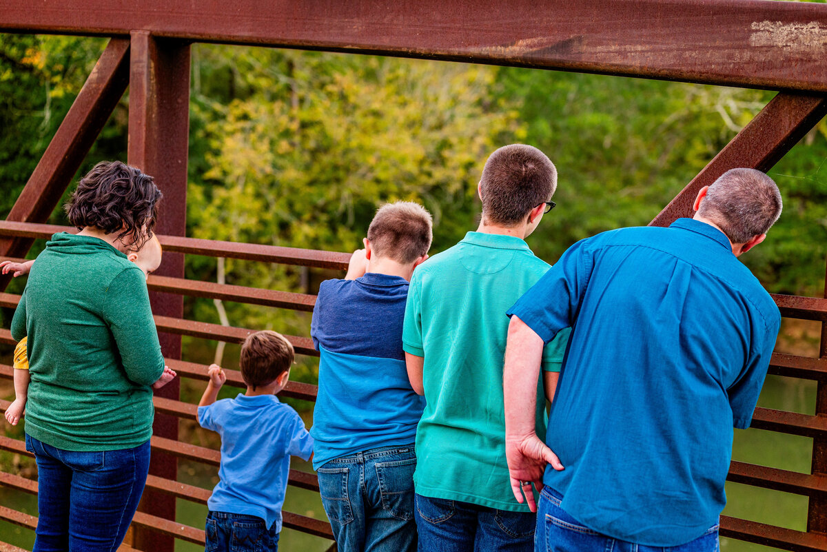 A family looks over a bridge at Hayes Nature Preserve during family photos in Alabama
