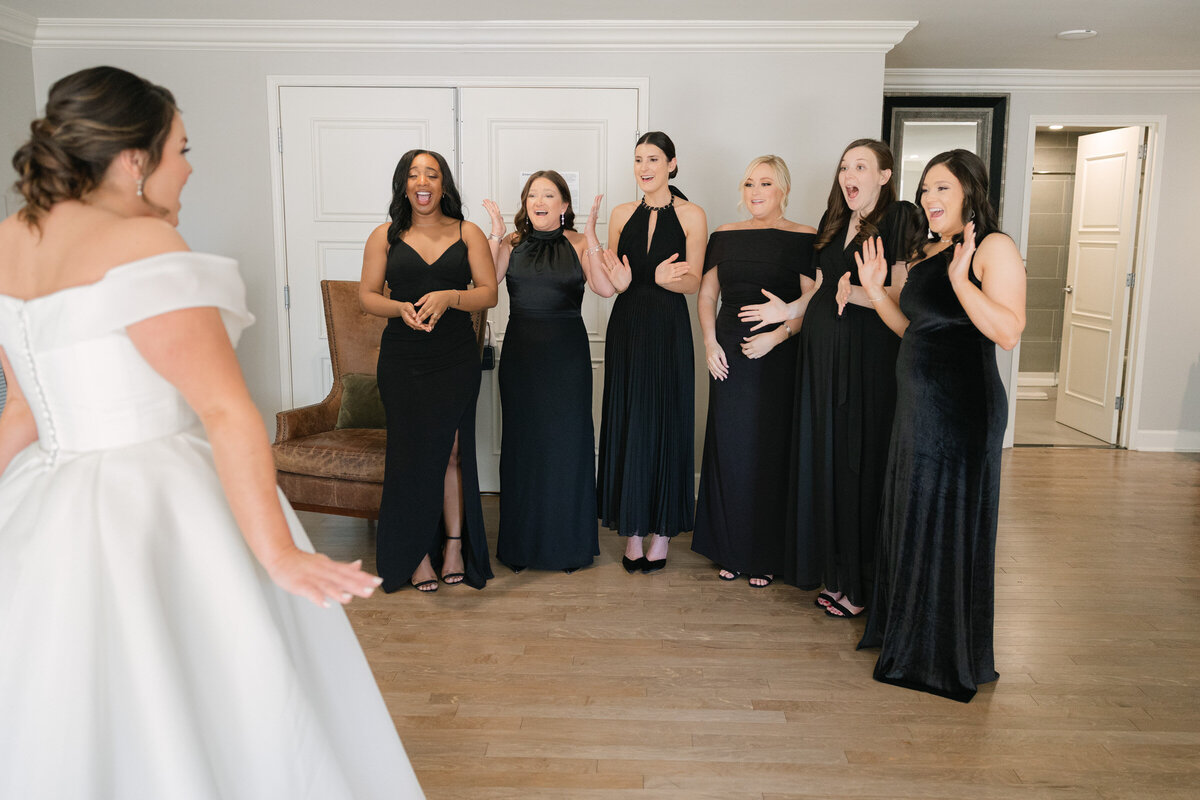 bride sharing a first look with bridesmaids dressed in black at The Adolphus in Dallas, capturing a joyful and elegant wedding moment.