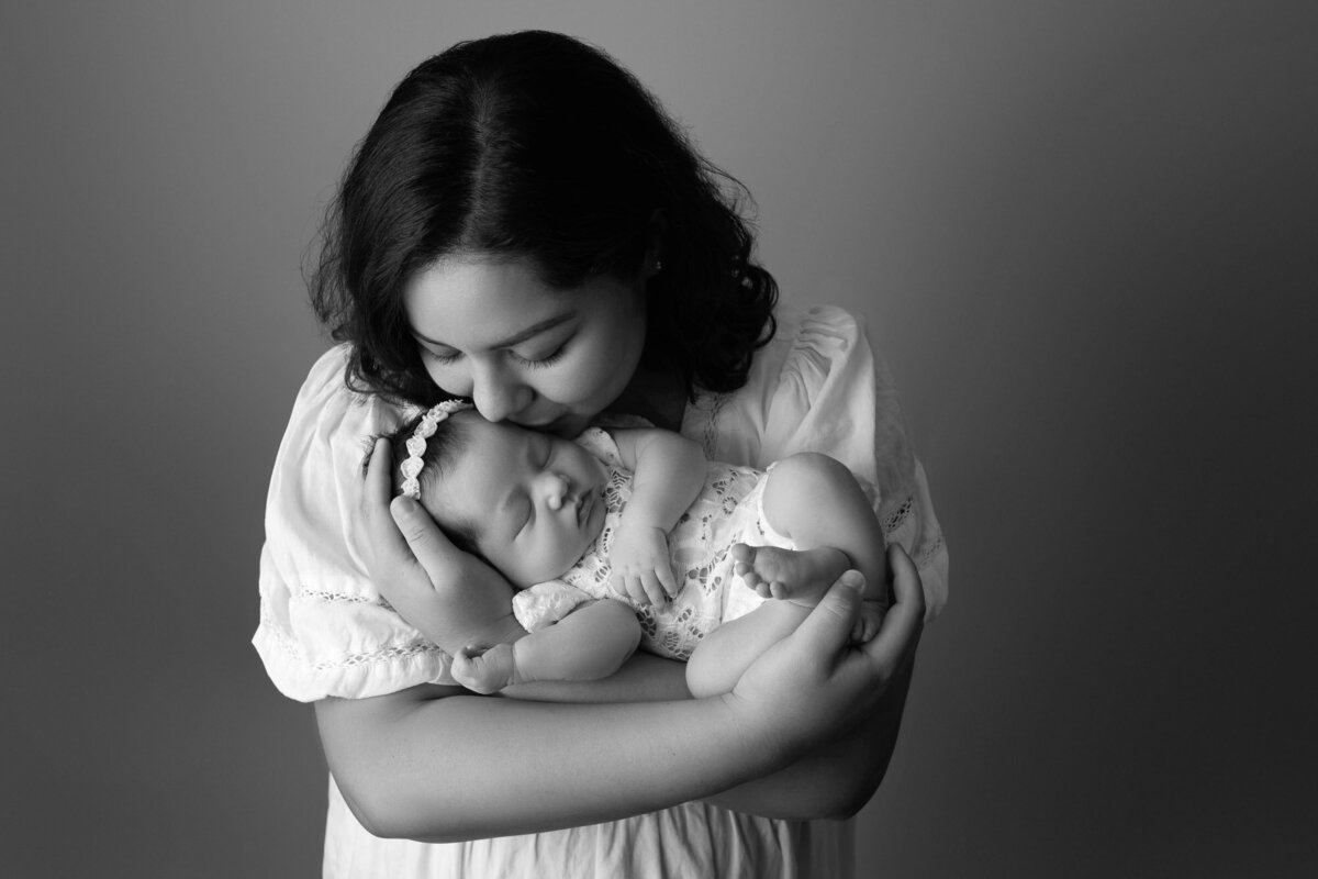 Black white mother kissing newborn Lakeway lifestyle family photographer