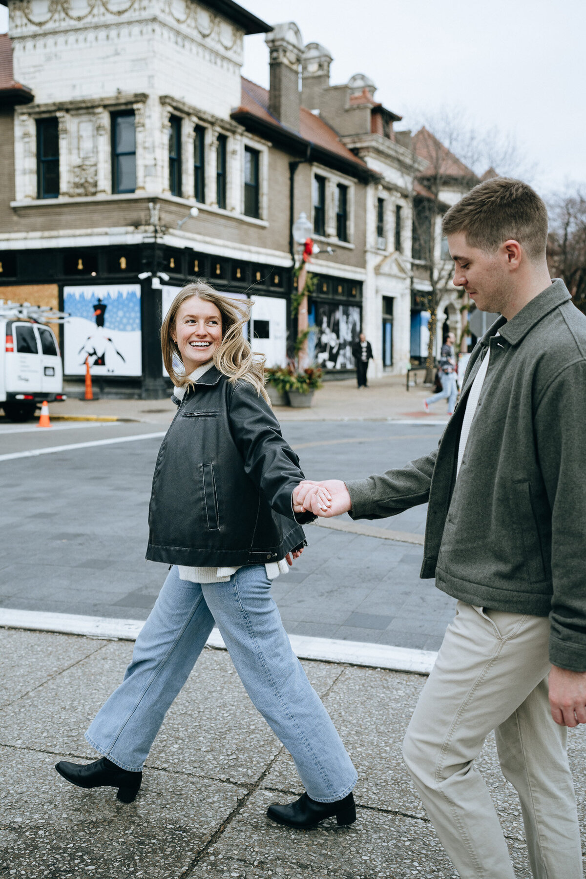 newly engaged couple holding hands and crossing the street