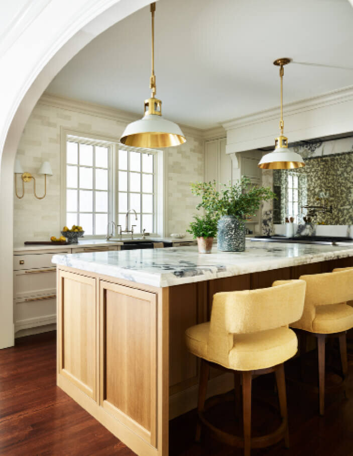 Kitchen designers in Boston created white cabinets and an oak island with brass lighting from Urban Electric, featuring traditional interior design in Milton, MA.