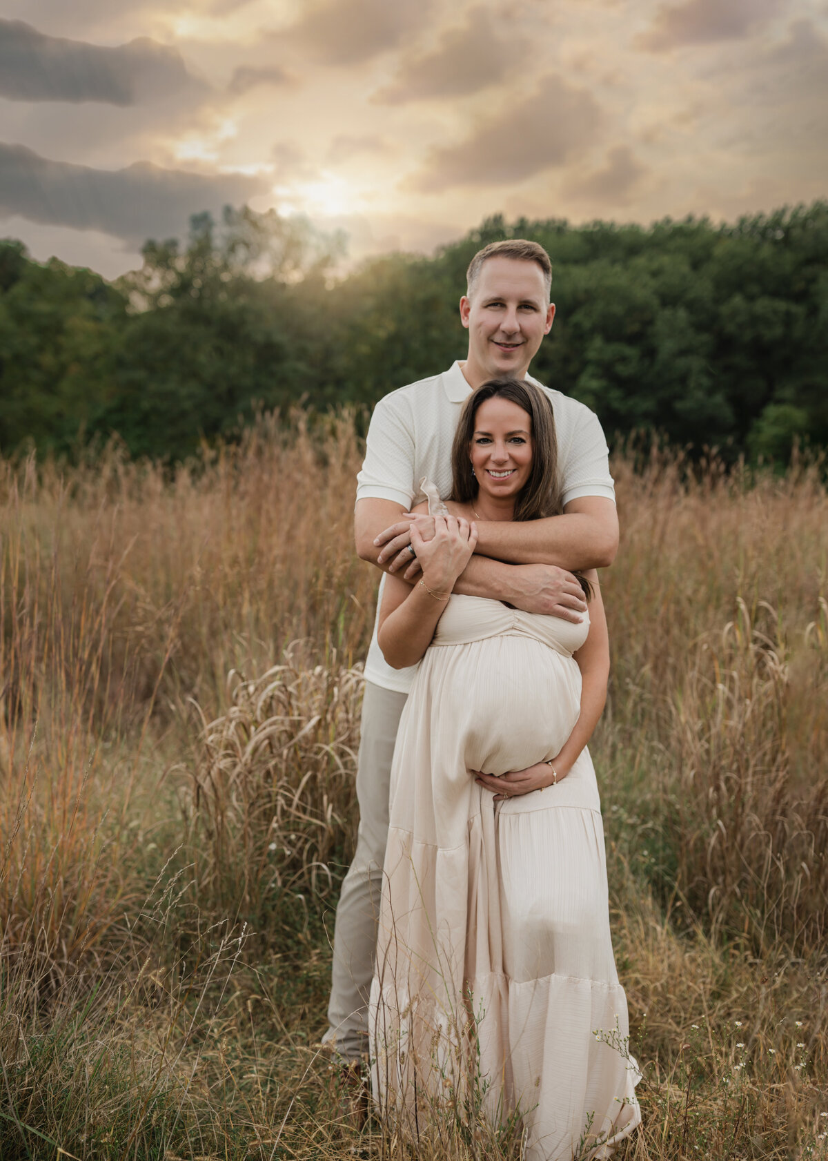 husband and pregnant wife in pink silk maternity gown holding baby bump for maternity photoshoot