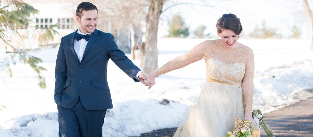 Bride and groom laughing and walking in the snow photo