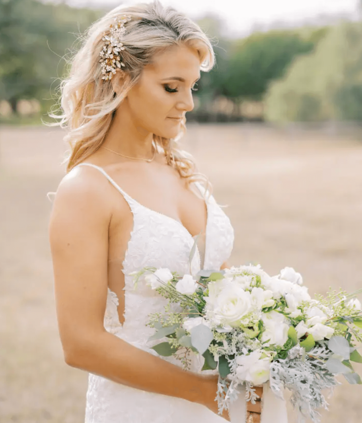 Bride holding a white bouquet in San Antonio, featuring soft glam makeup, voluminous waves, and flawless bridal hair styling for a romantic outdoor wedding