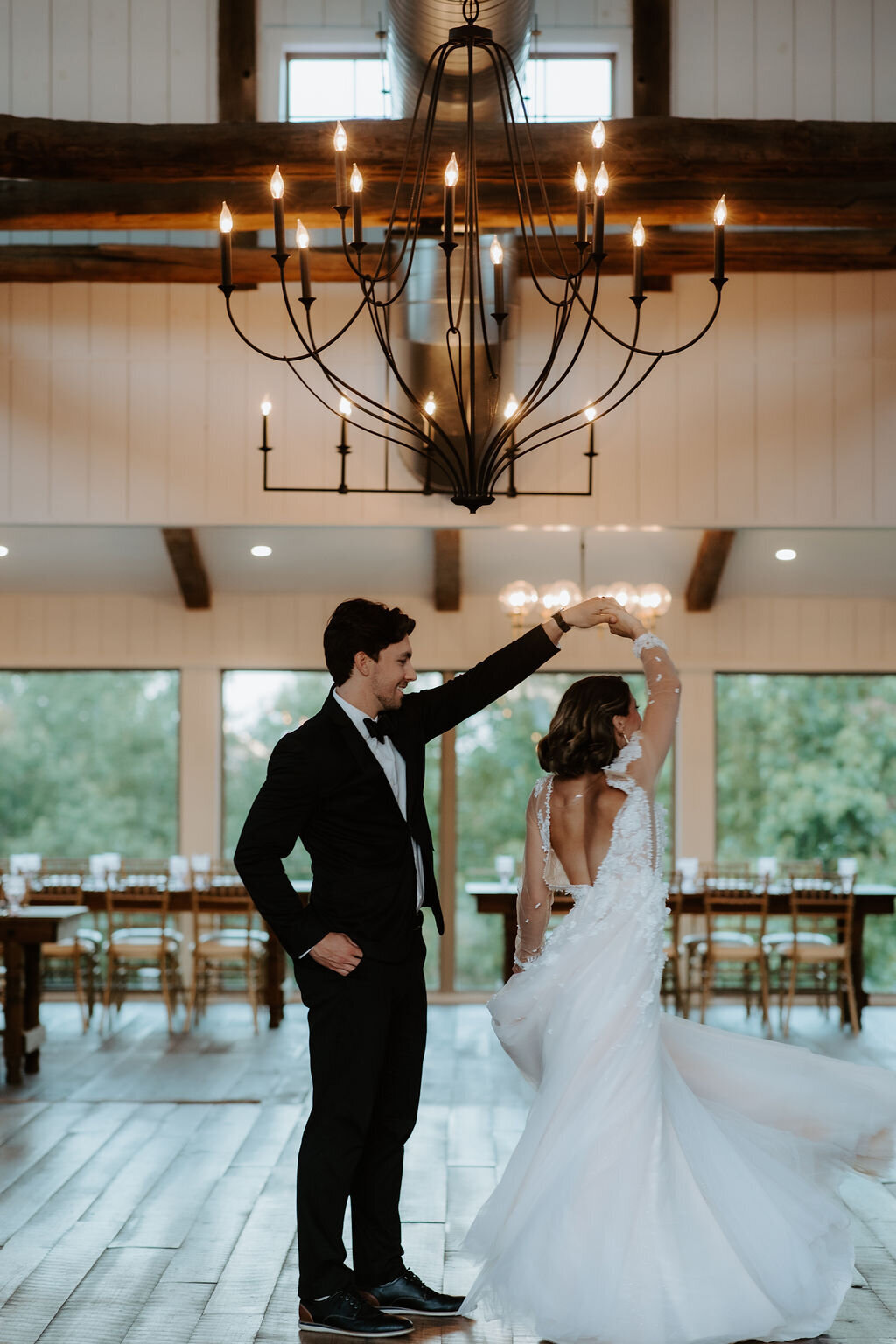 a bride and a groom in a black suit twirling during their first dance under the twinkling Pottery Barn chandeliers at Willowbrook wedding venue in PIttsburgh