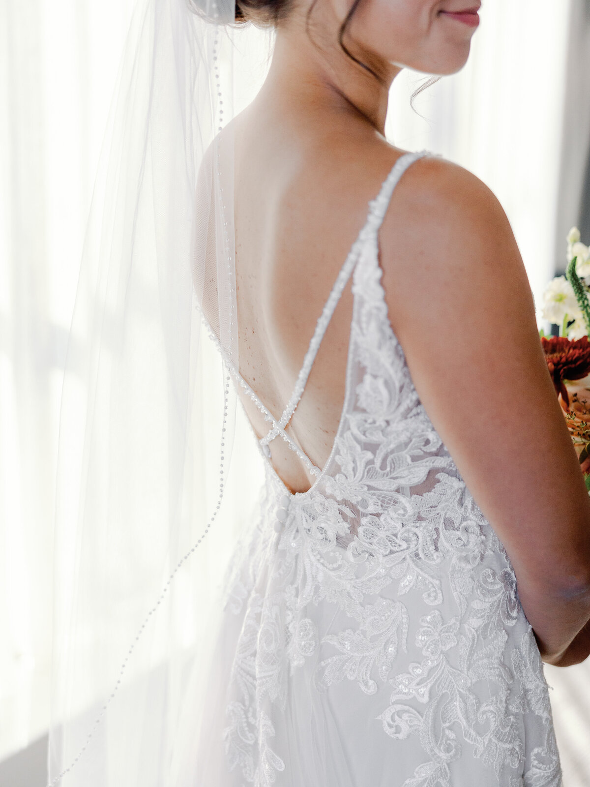A closeup of the back of a brides wedding dress to show off the beaded criss cross straps