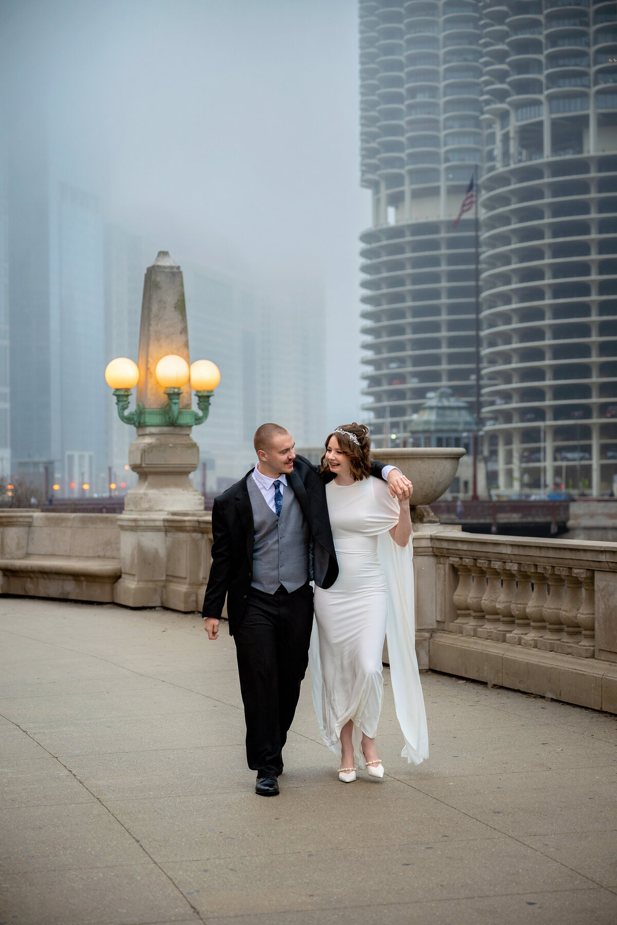 Documentary style wedding pictures of bride and groom walking and looking at each other with foggy background of Chicago